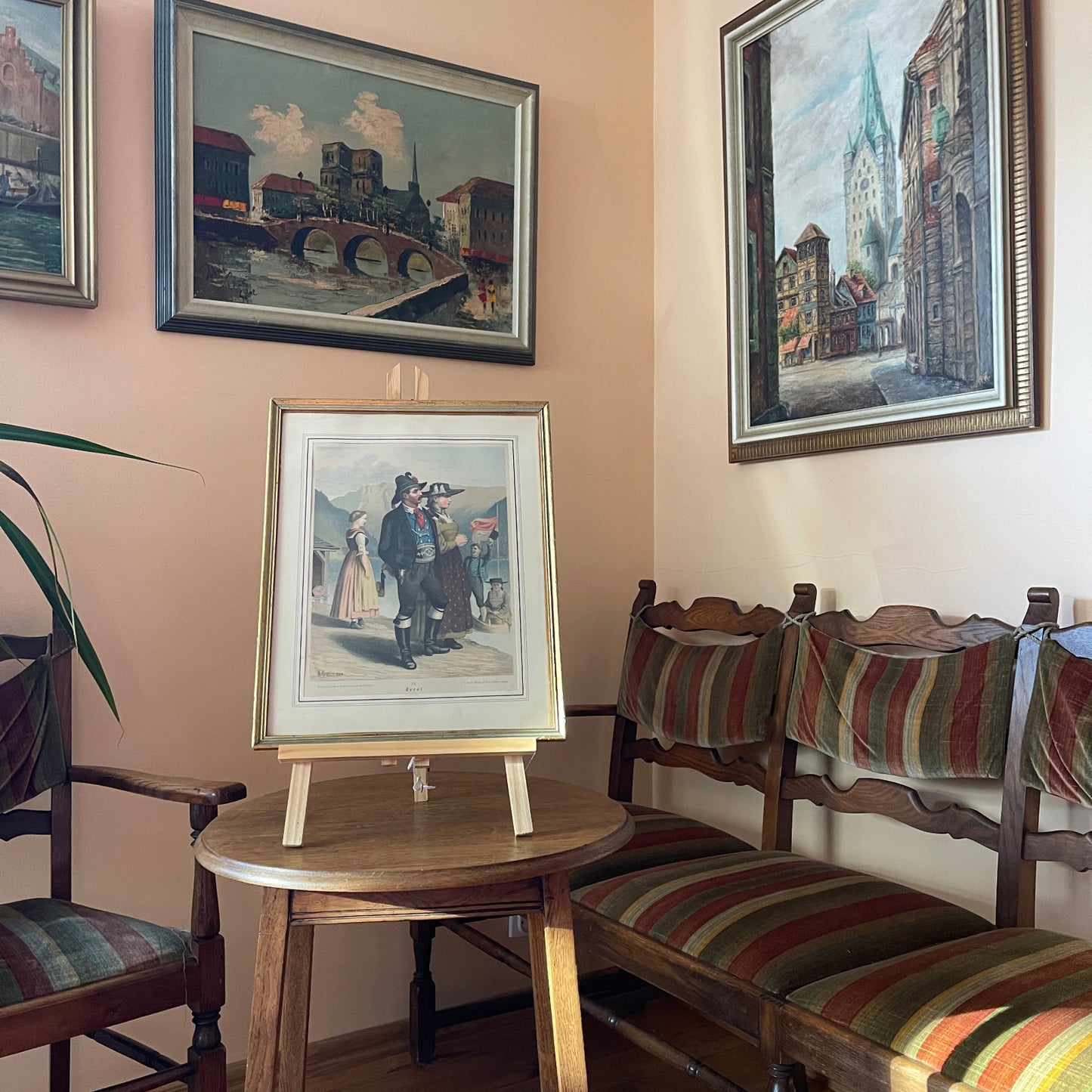 Room interior with framed artworks on the wall and wooden chairs with striped cushions.