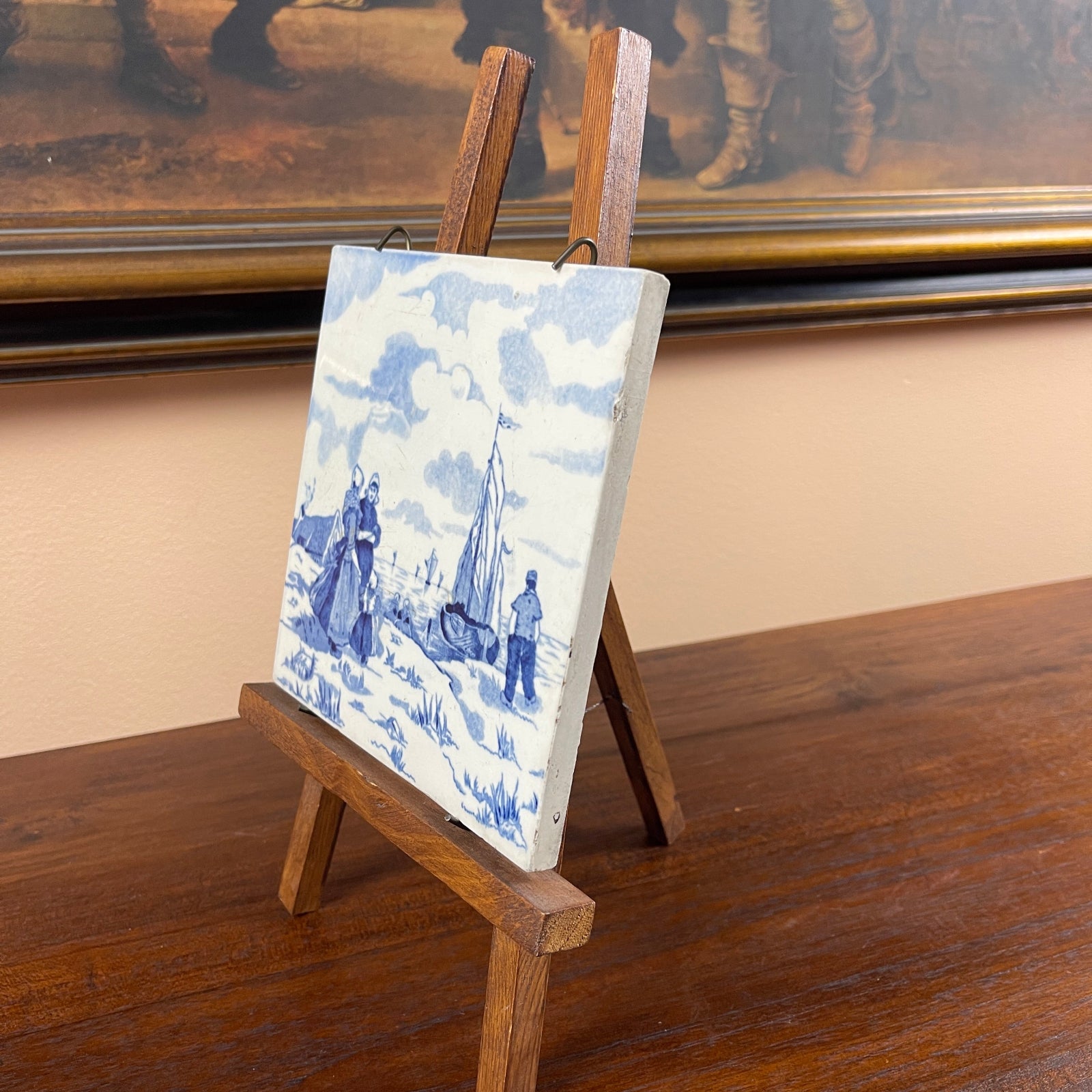 Small blue and white ceramic tile with a wooden easel on a wooden surface