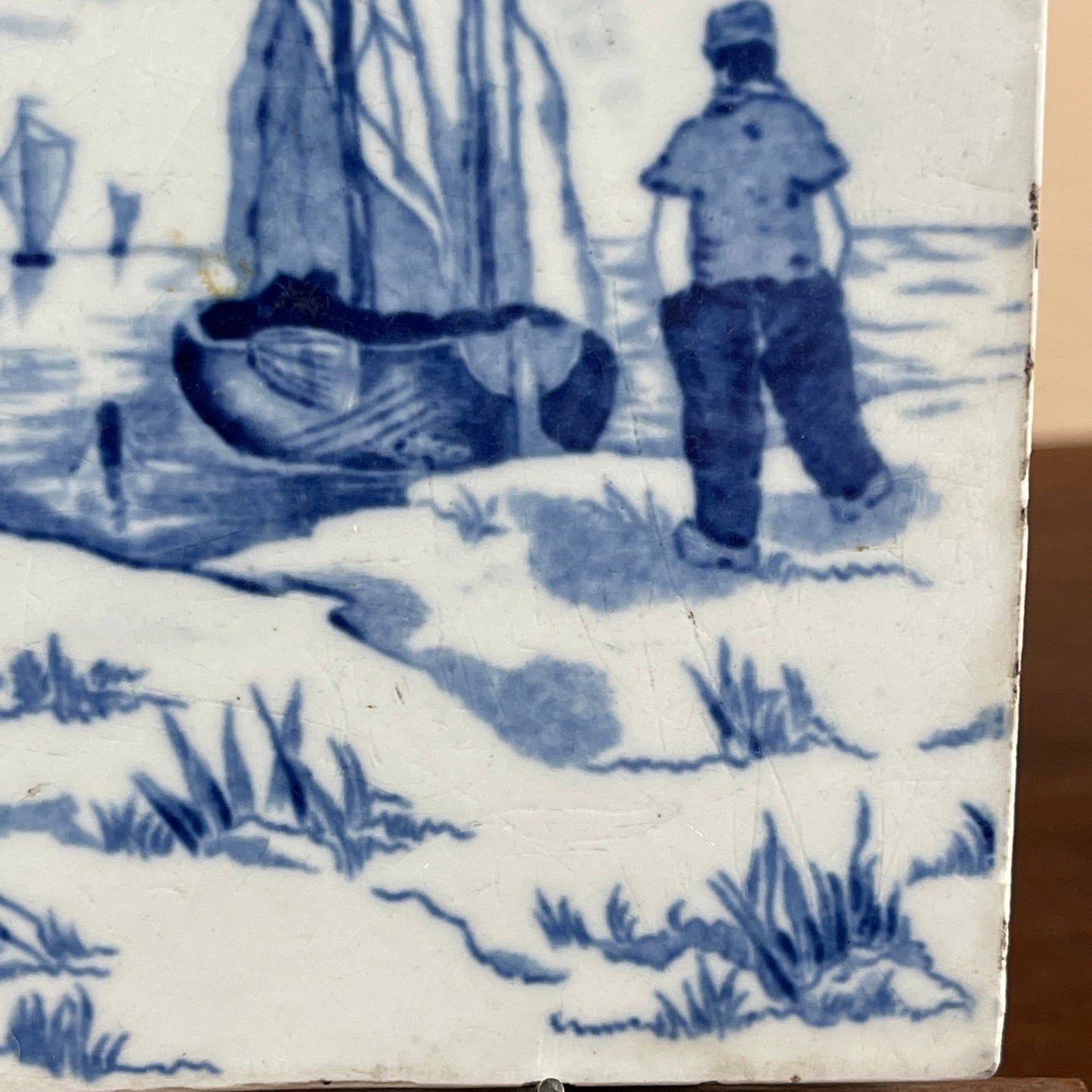 Delft blue tile with a scene of a man by a boat on a snowy landscape