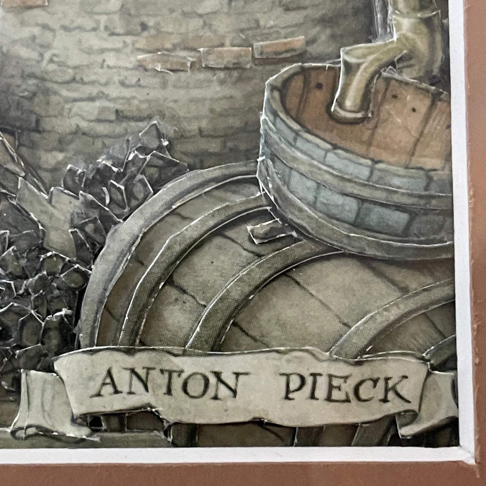 Decorative item with 'Anton Pieck' banner and metal elements against a stone wall background