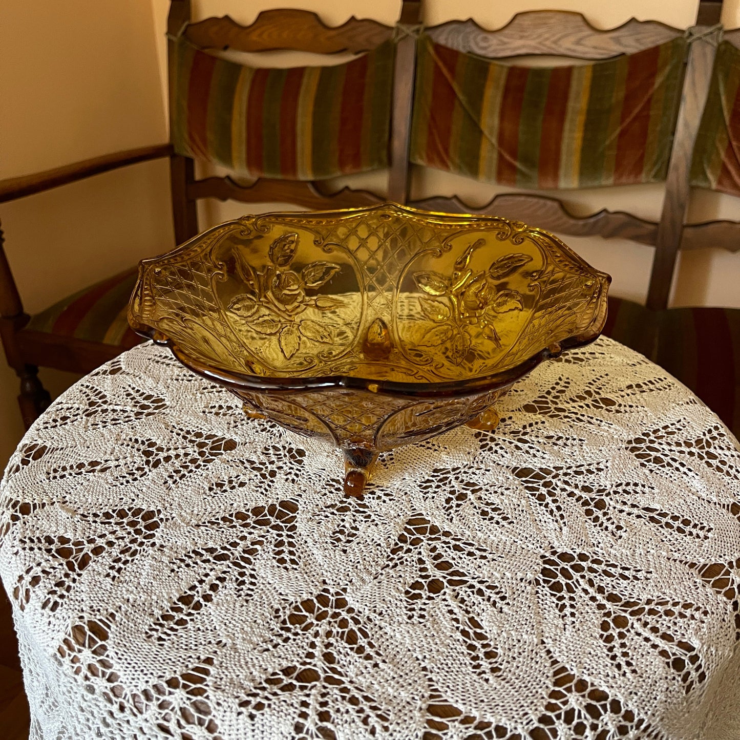 Decorative glass bowl on a lace tablecloth with a chair in the background