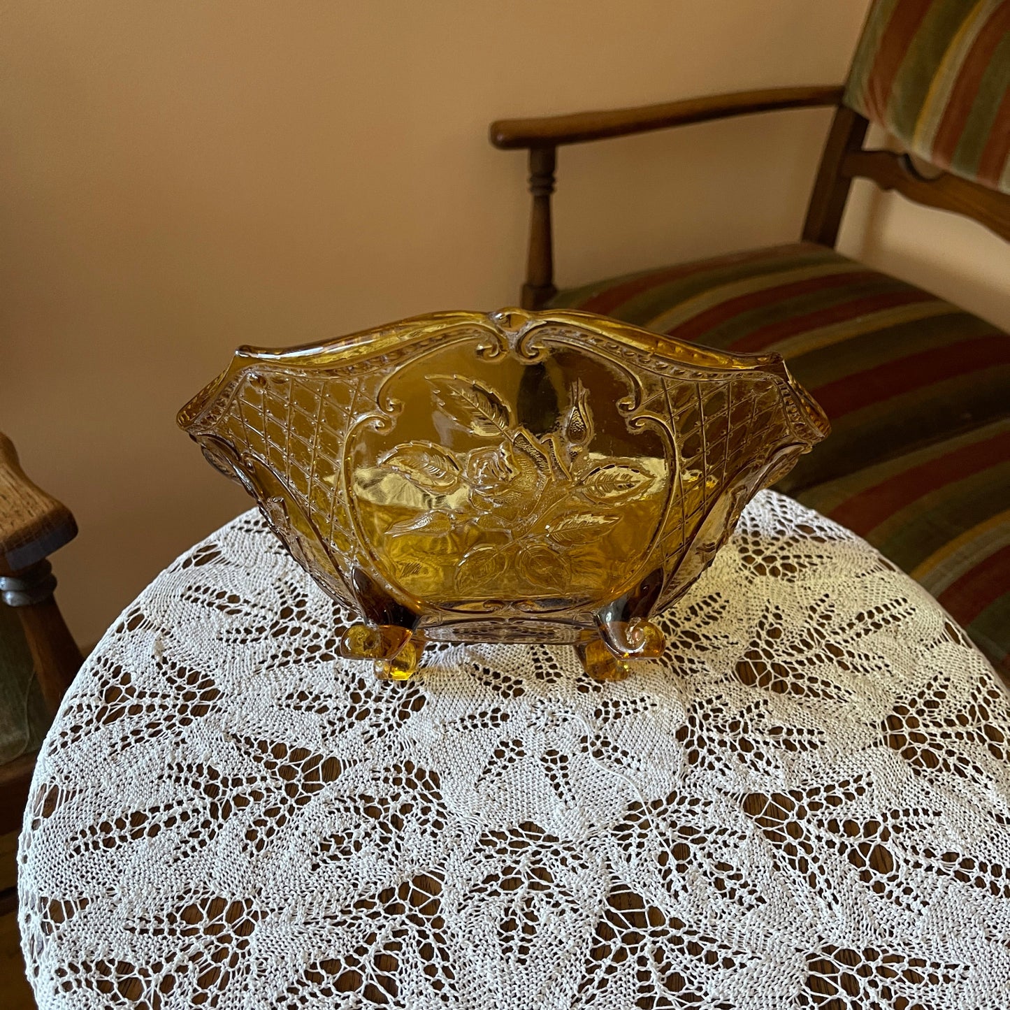 Decorative glass bowl on a lace tablecloth with a chair in the background