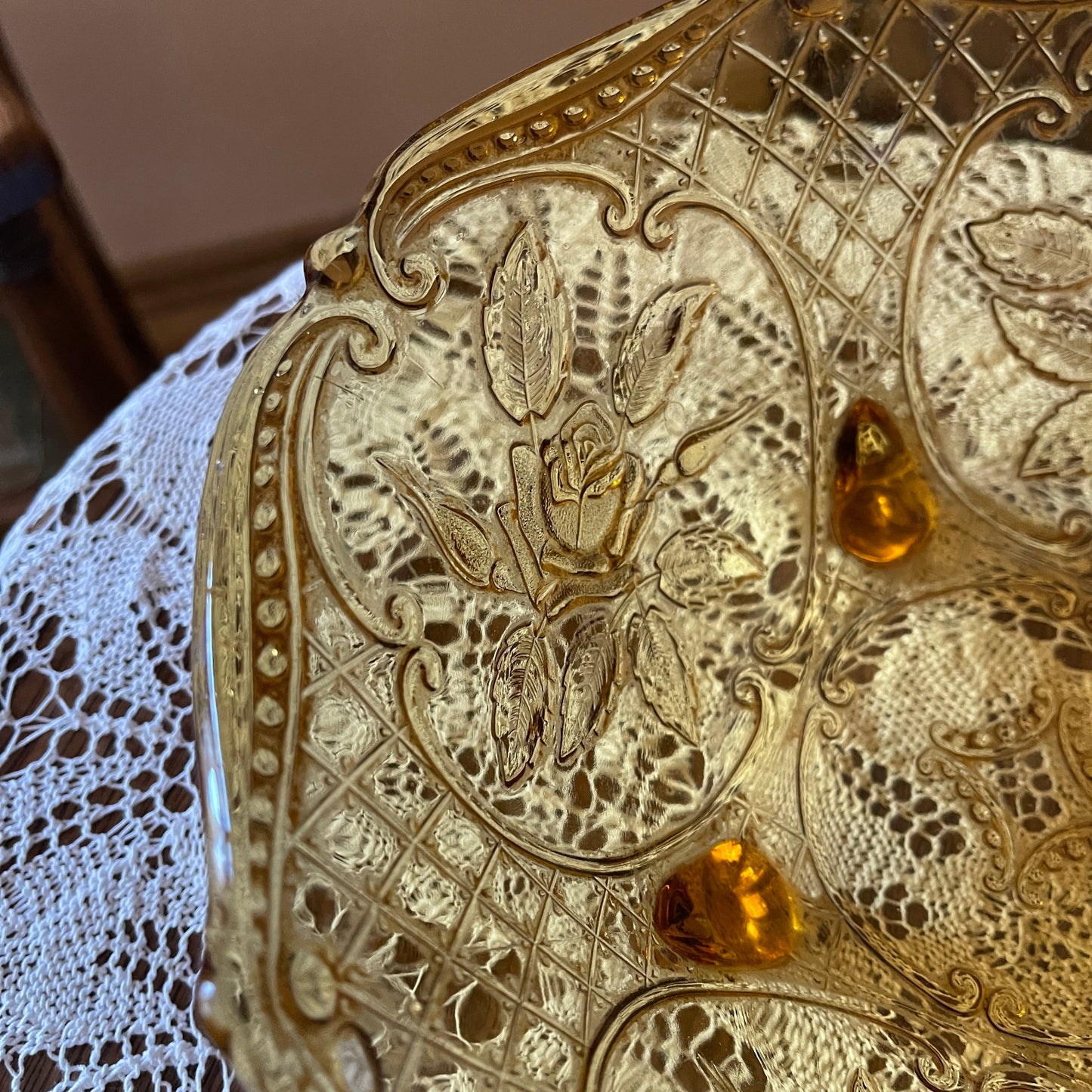Decorative metal dish with floral patterns on a lace tablecloth
