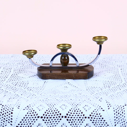 A chrome metal candlestick with brass elements on a wooden base, designed in an Art Deco style.