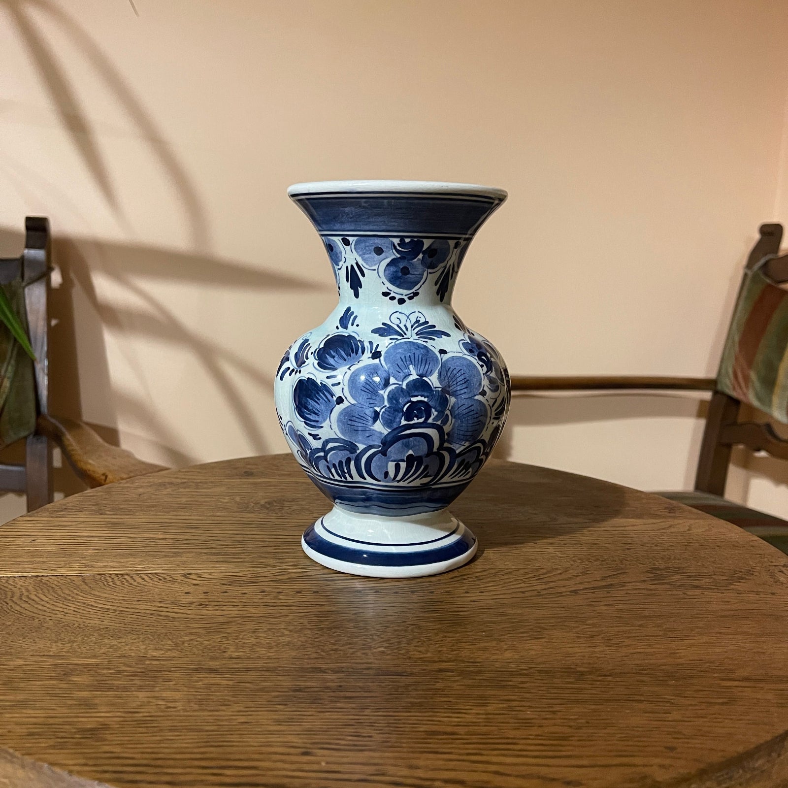 Blue and white floral-patterned vase on a wooden table with a beige wall background