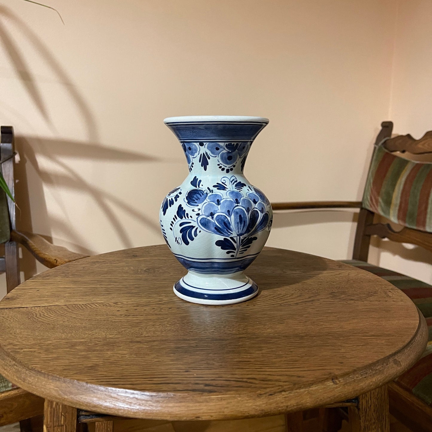 Blue and white floral-patterned vase on a wooden table with a neutral background