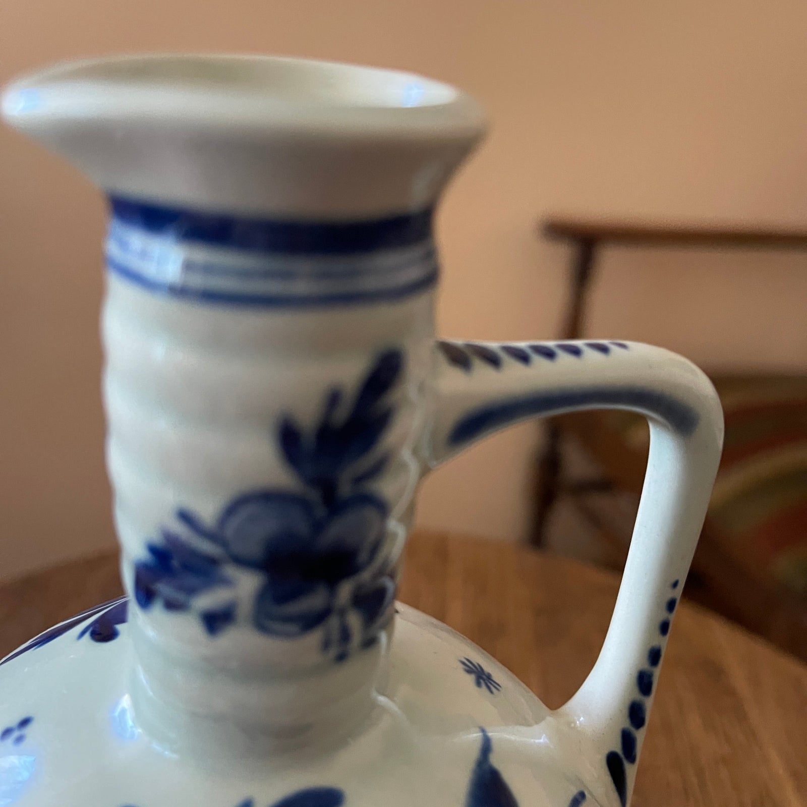 White ceramic vase with blue floral patterns on a wooden surface.