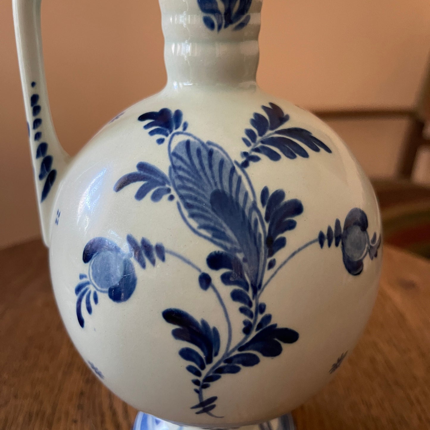 White ceramic vase with blue floral patterns on a wooden surface.