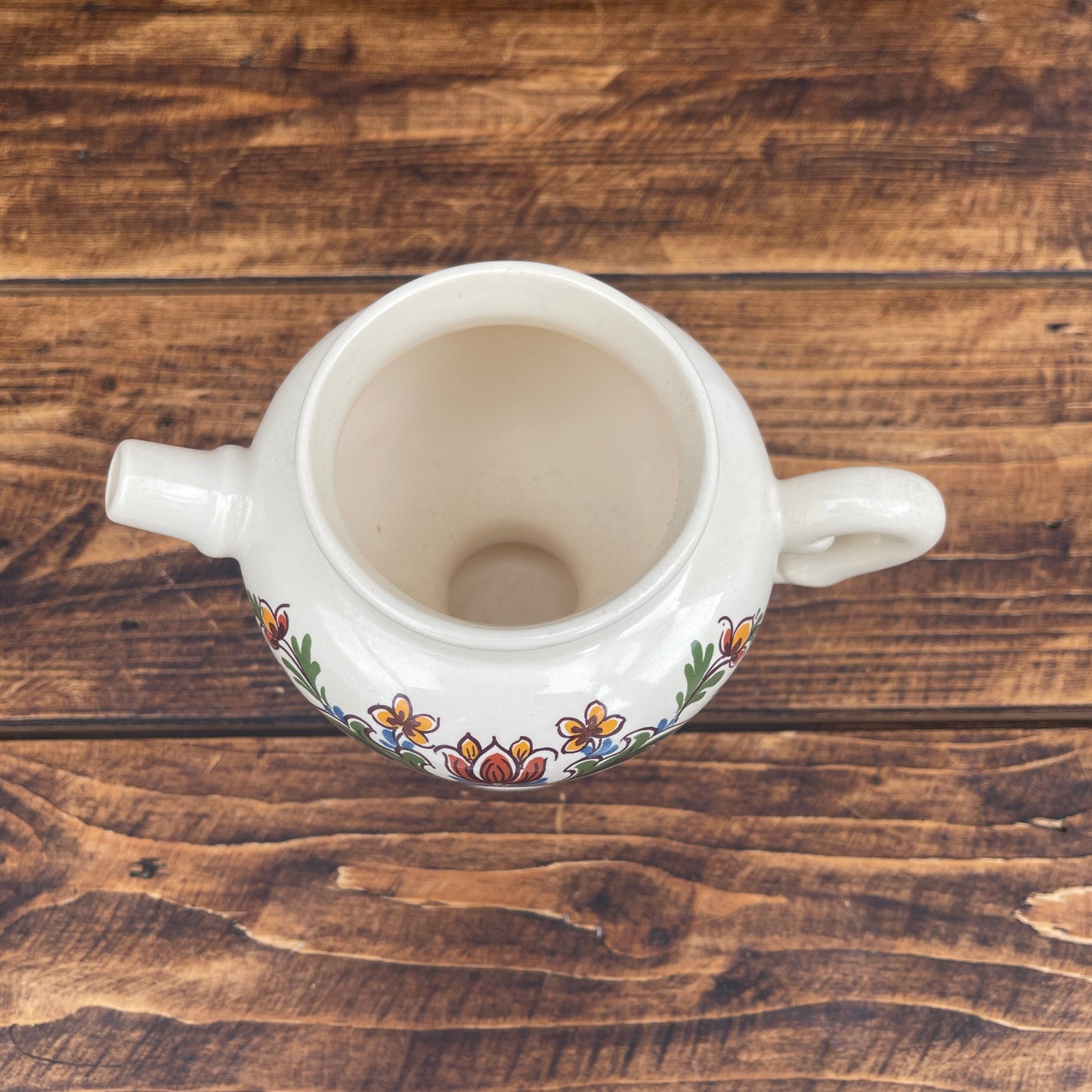 White ceramic pot with floral patterns on a wooden surface