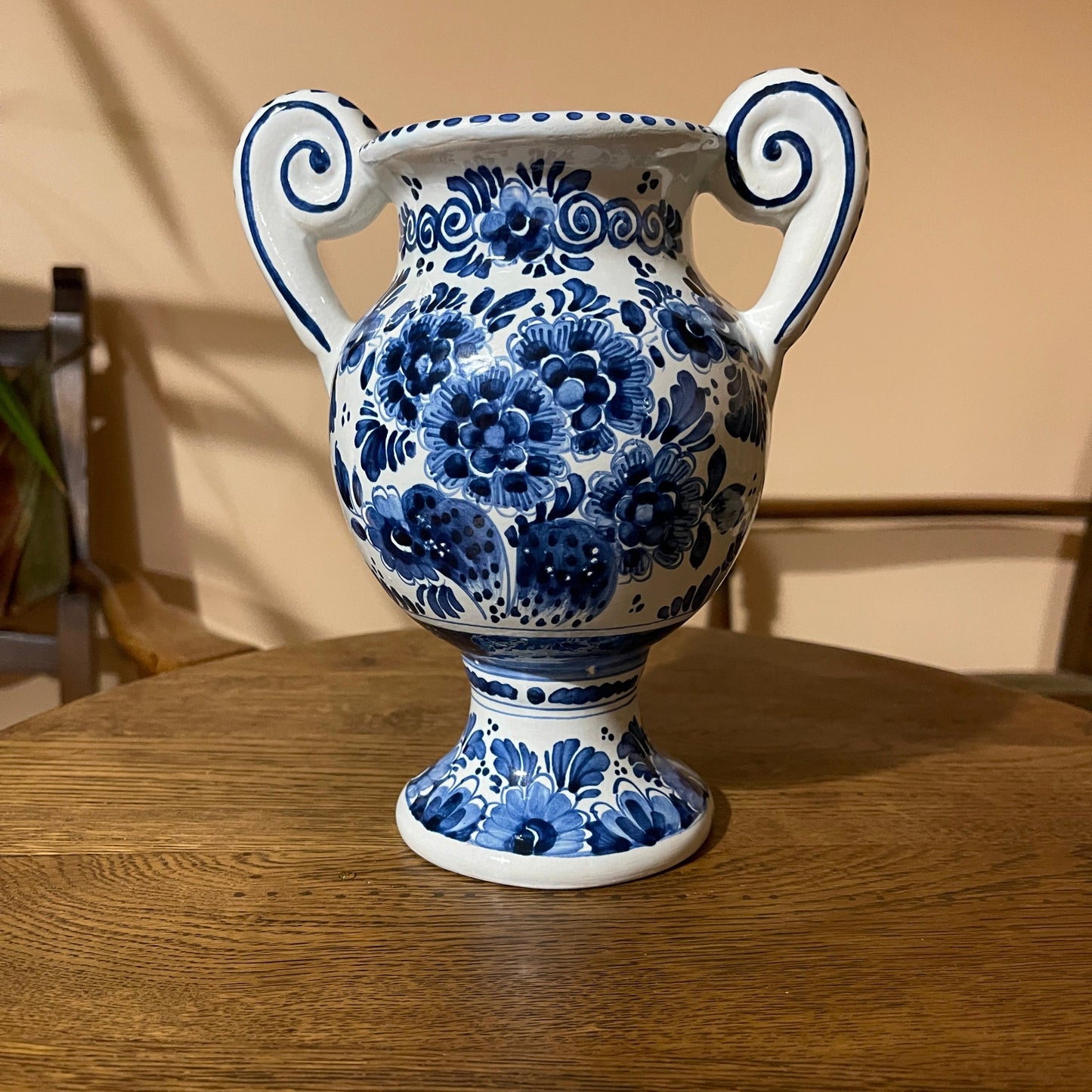 Blue and white floral-patterned vase with two handles on a wooden surface.