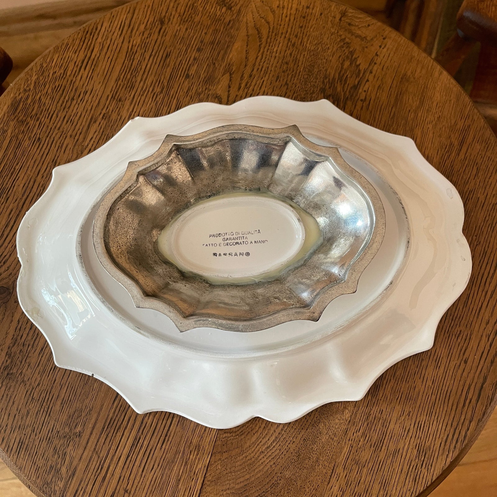 Decorative white plate with scalloped edge on a wooden surface