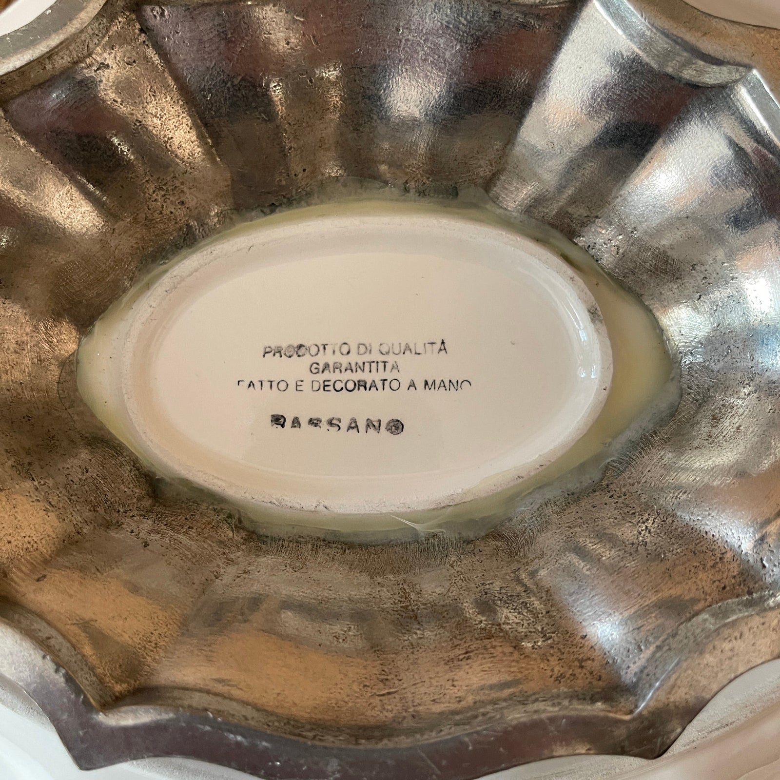 Decorative metal bowl with a brand name on a white background