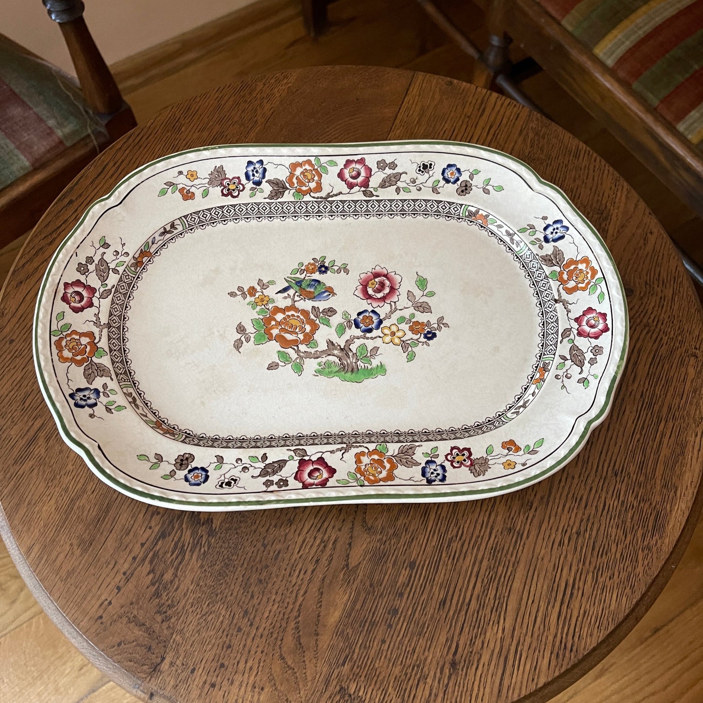 Decorative platter with floral and bird design on a wooden table