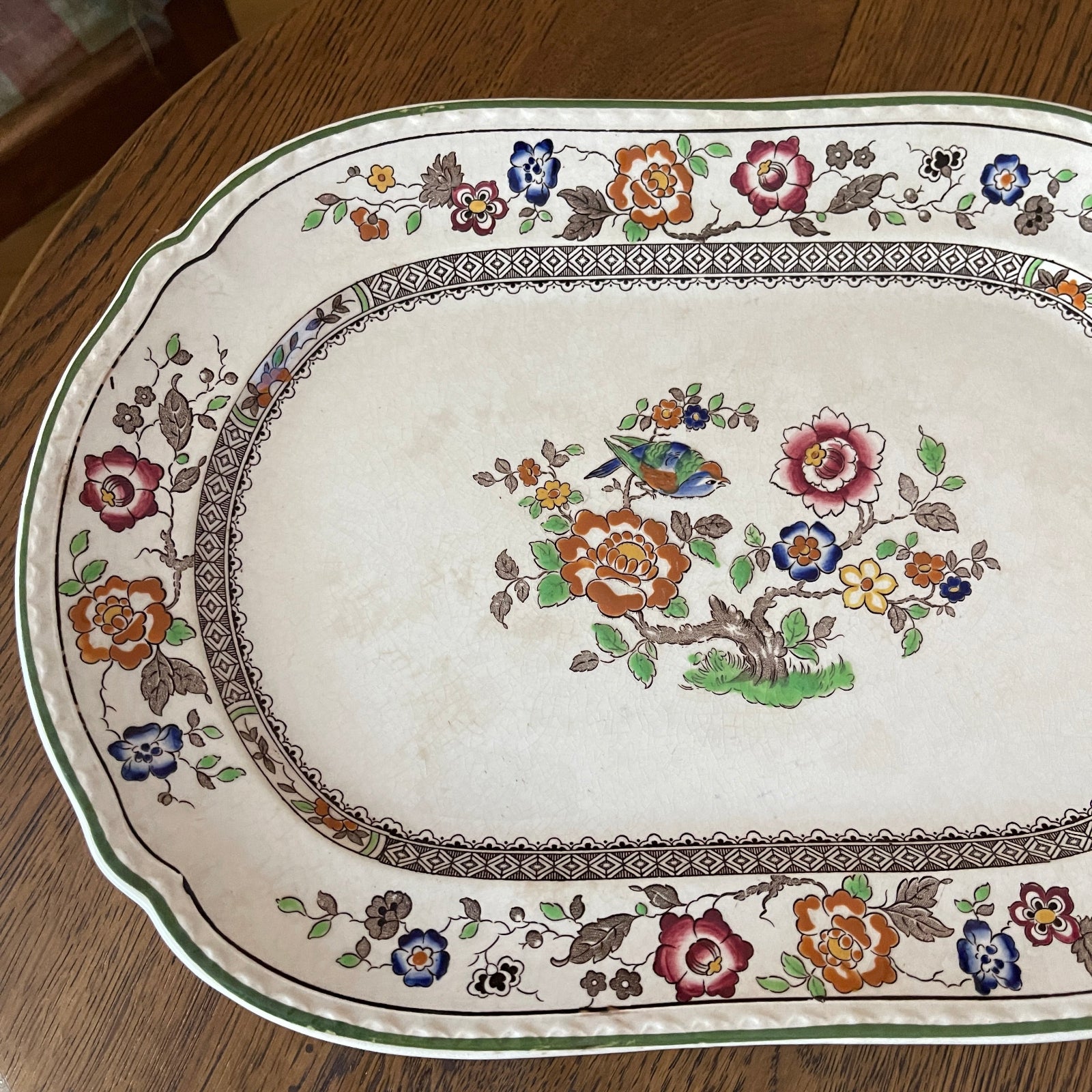 Decorative tray with floral and bird pattern on a wooden surface