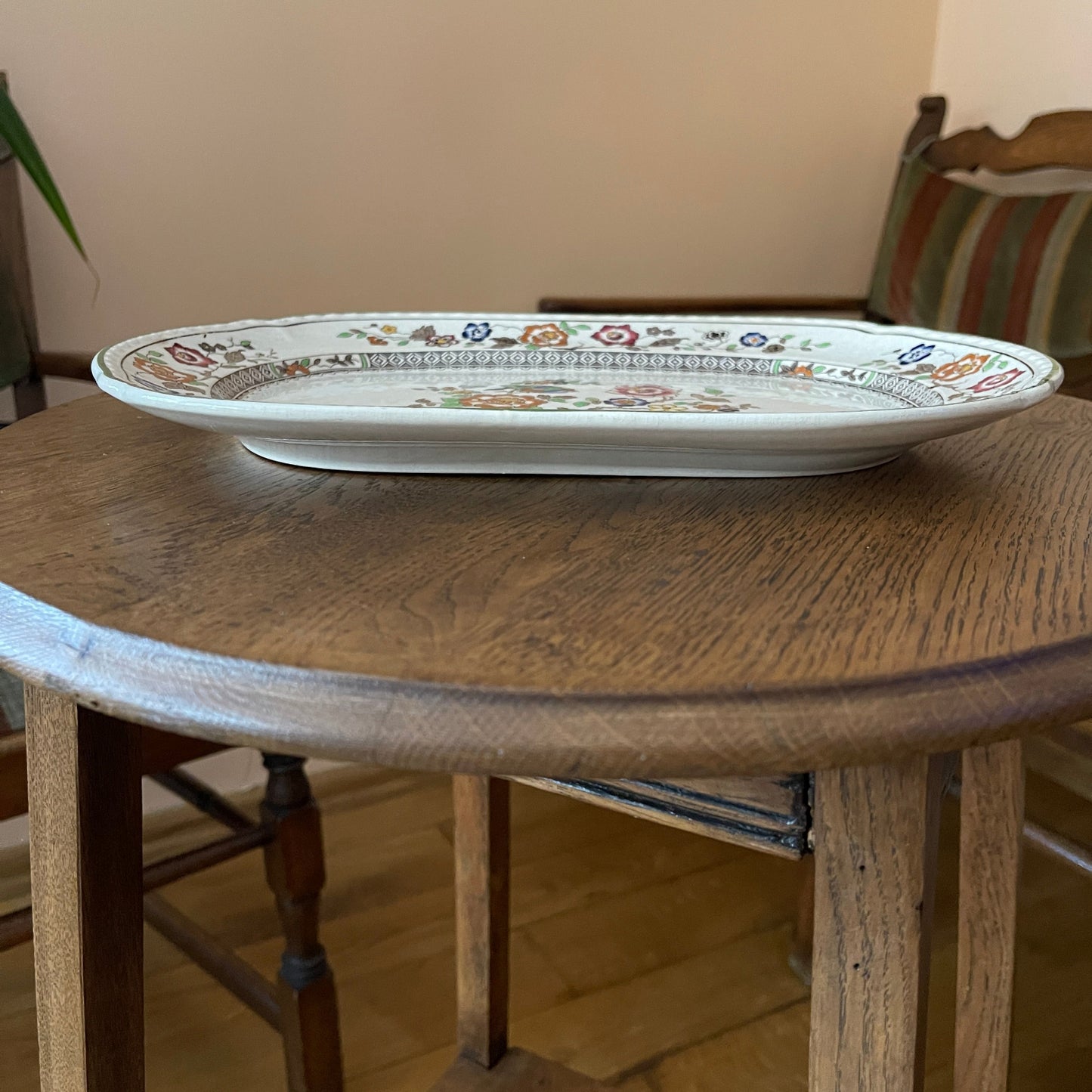 Decorative plate on a wooden table with a chair in the background