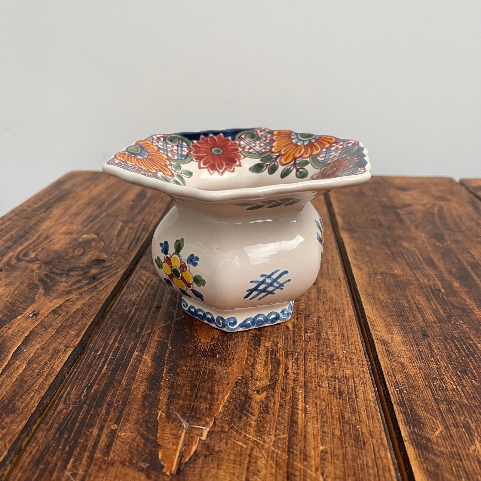 Decorative ceramic footstool with colorful floral patterns on a wooden surface.