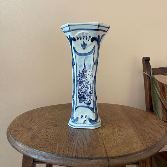 Blue and white ceramic vase on a wooden table against a beige wall