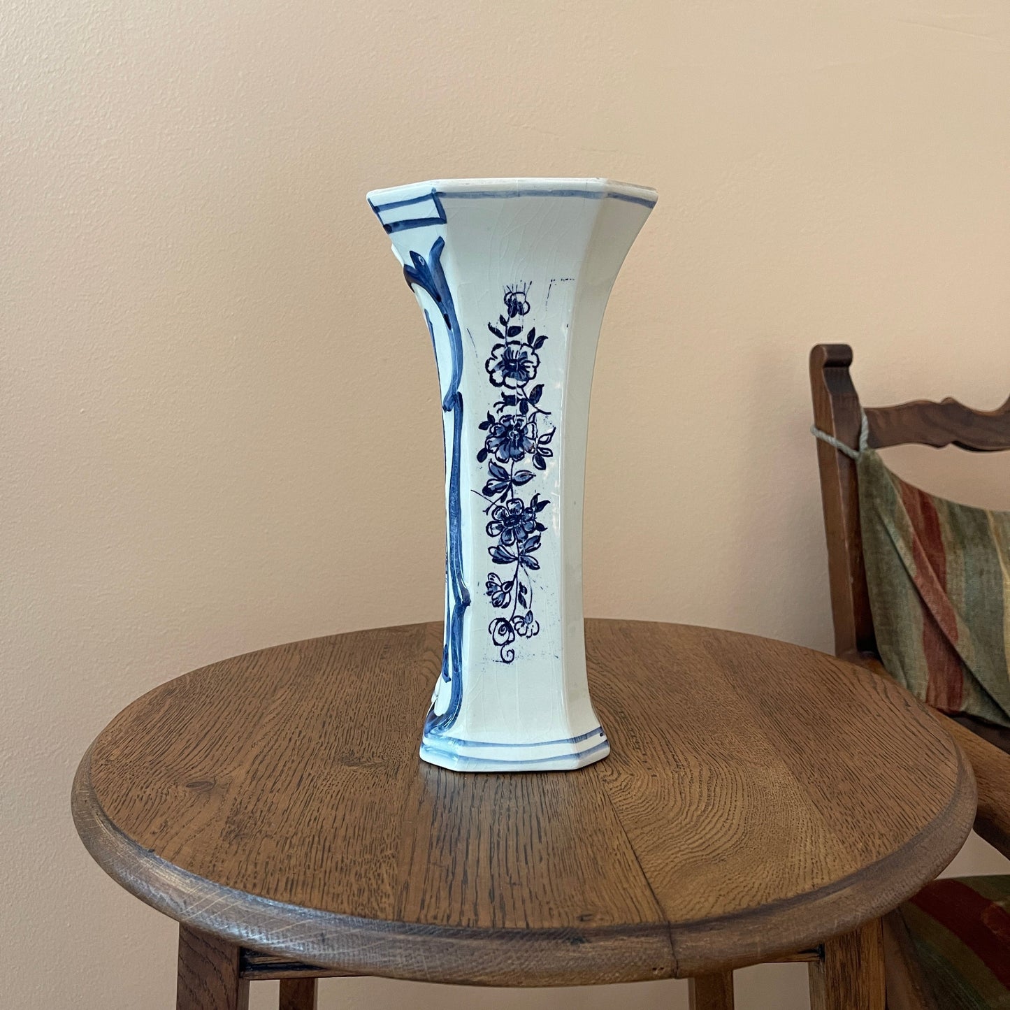 White vase with blue floral patterns on a wooden table against a beige wall