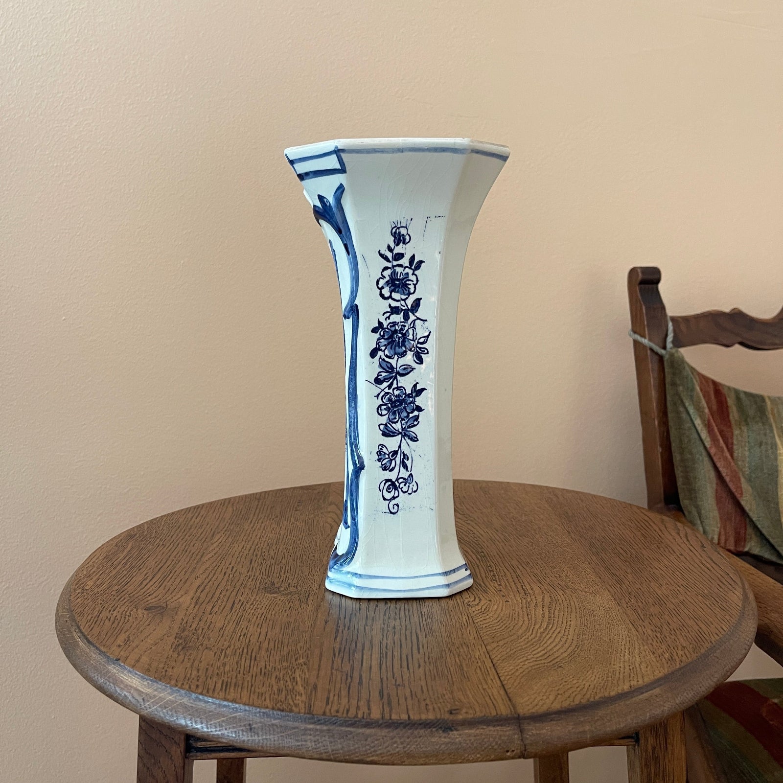 White vase with blue floral patterns on a wooden table against a beige wall