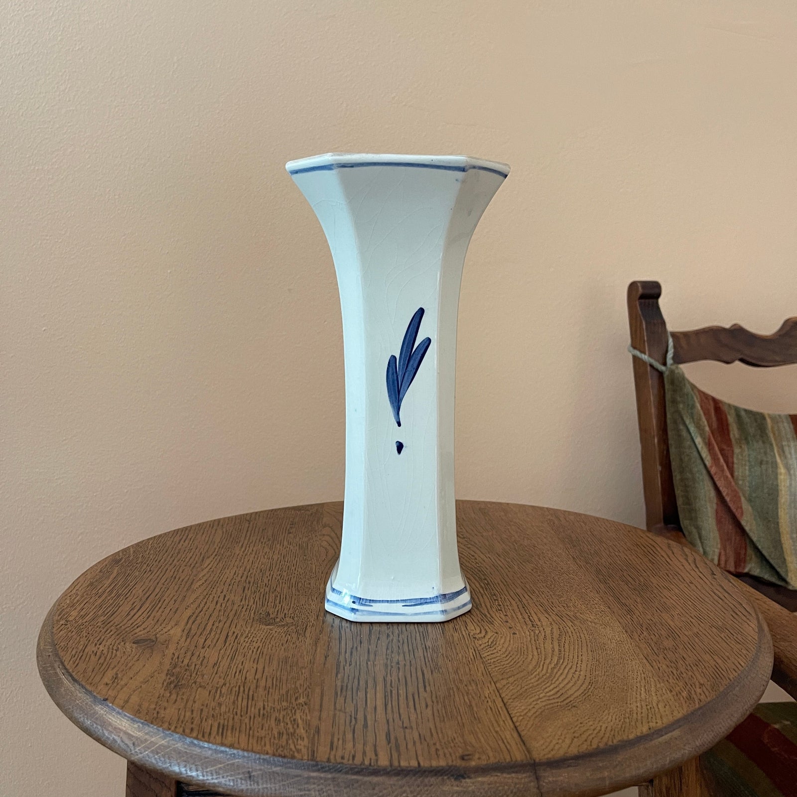 White vase with blue design on a wooden table against a beige wall