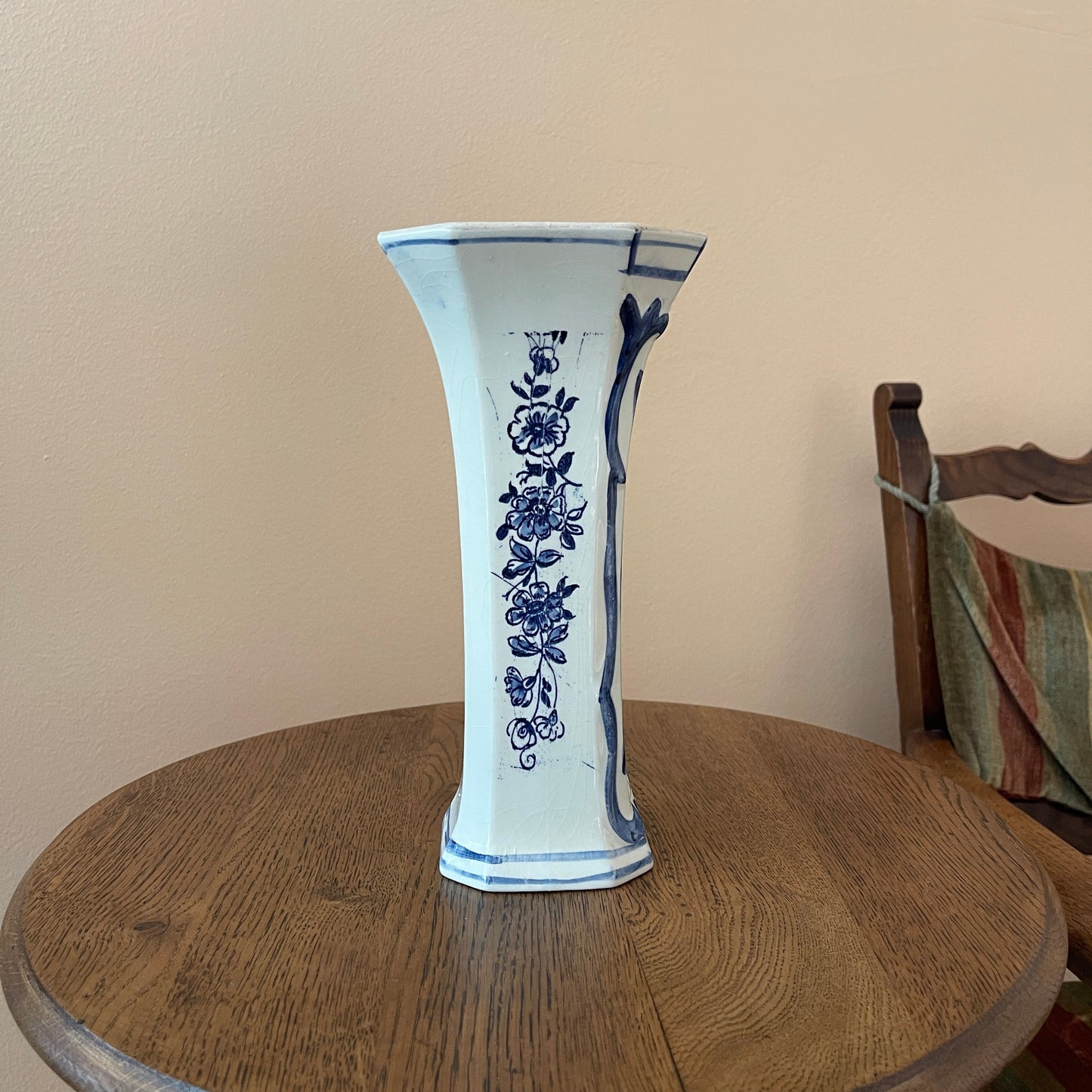 Ceramic vase with blue floral patterns on a wooden table against a beige wall.