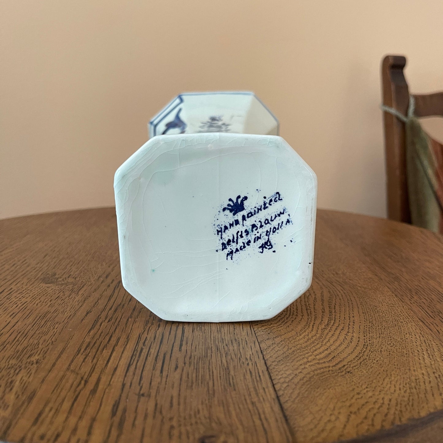 White ceramic vase with blue text on a wooden surface