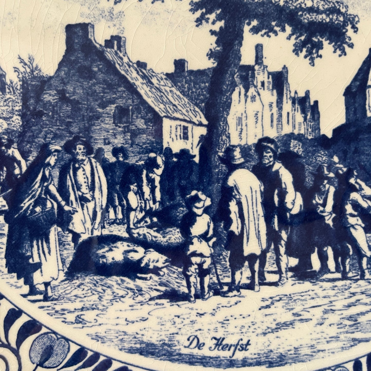 Vintage illustration of a village scene with people and buildings, labeled 'De Herfst'.