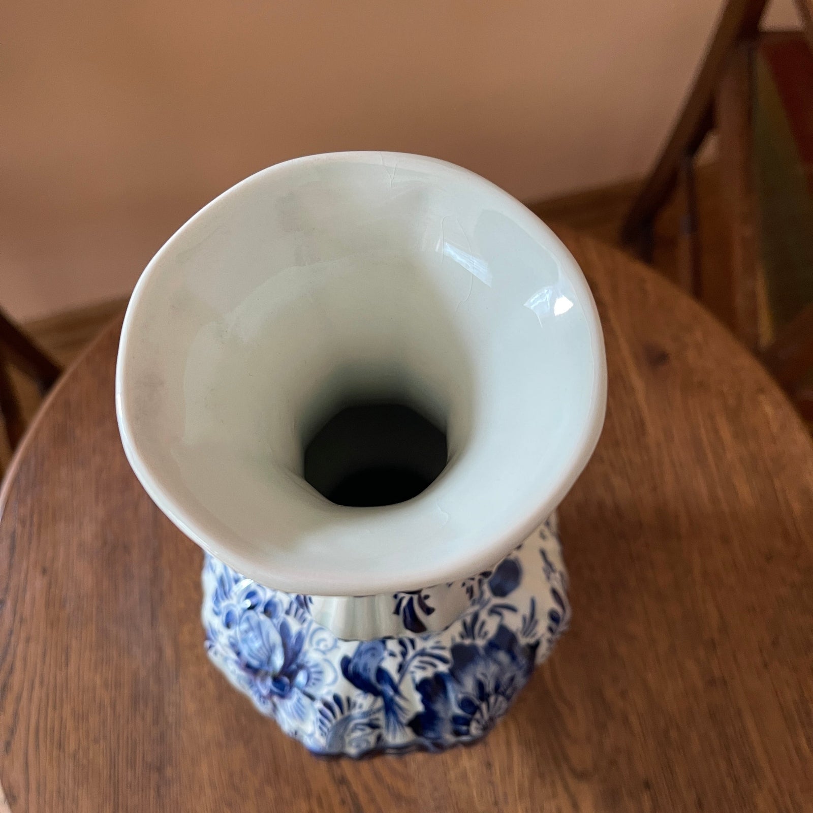 White ceramic vase with blue floral patterns on a wooden surface