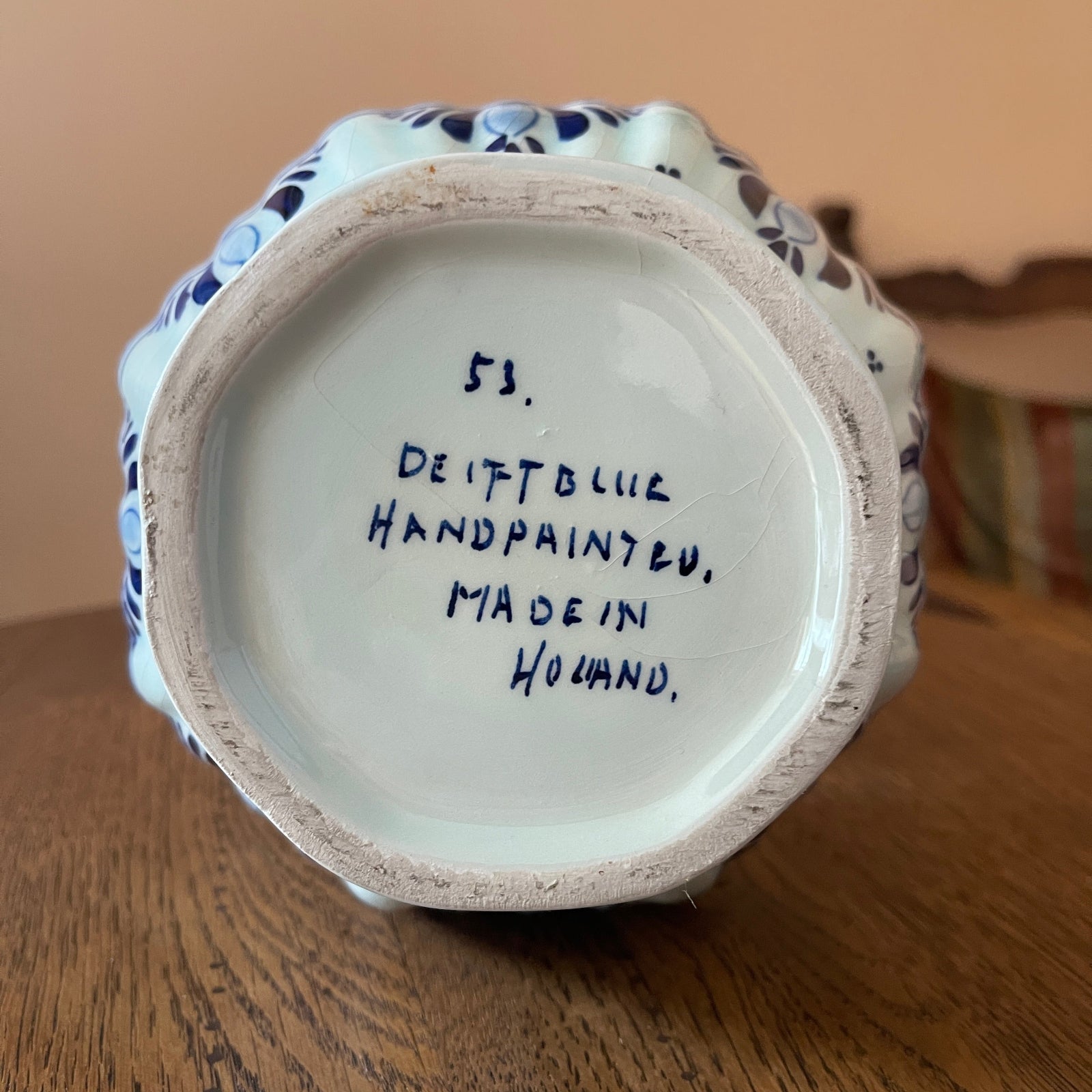 Ceramic vase with 'Deft Blue Handpaint' text on a wooden surface