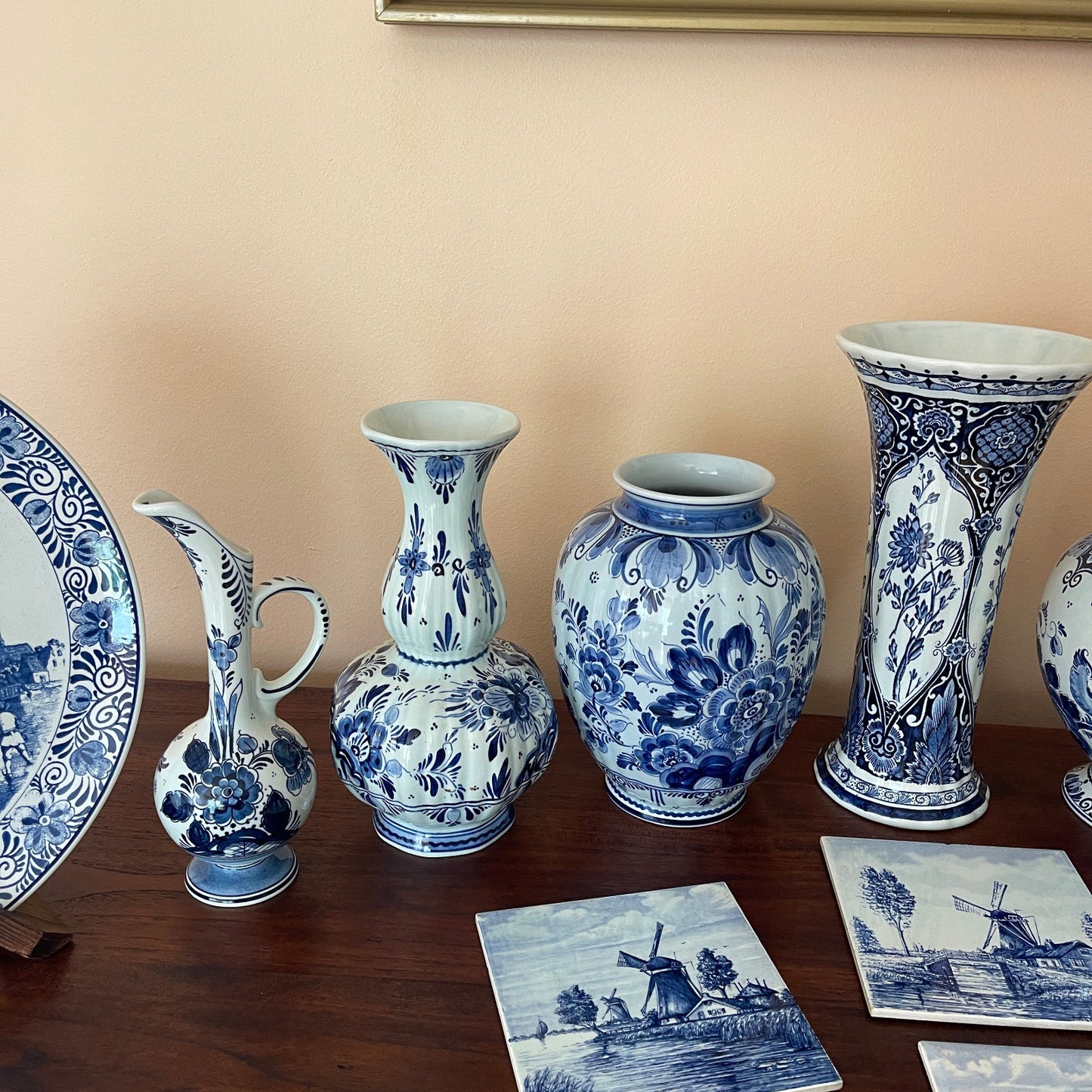 Collection of blue and white ceramic items on a wooden surface with a beige wall background.