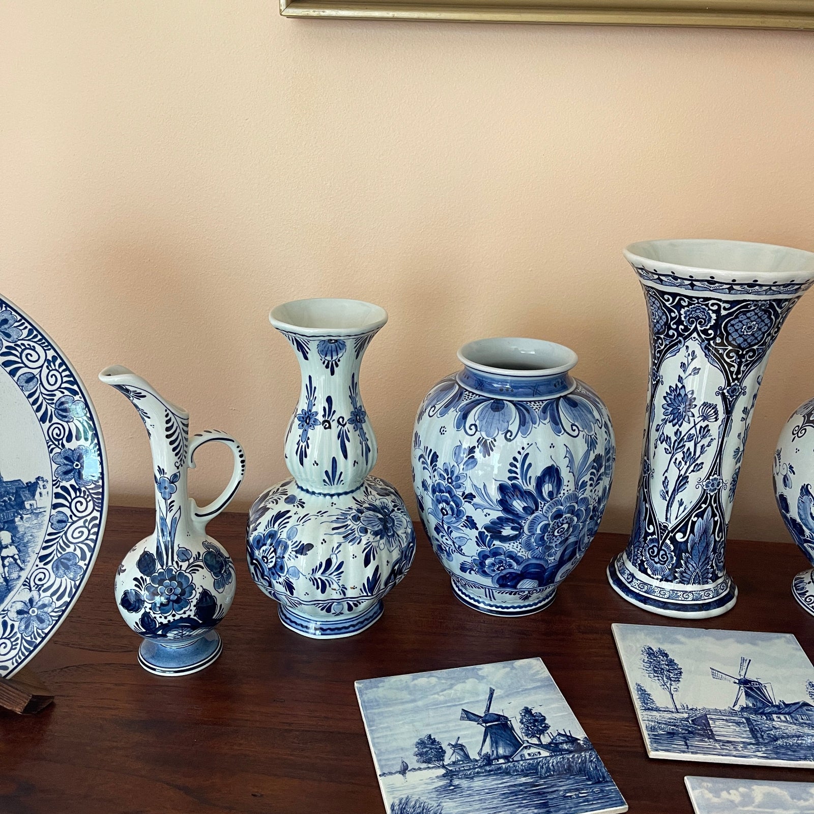 Collection of blue and white ceramic items on a wooden surface with a beige wall background.