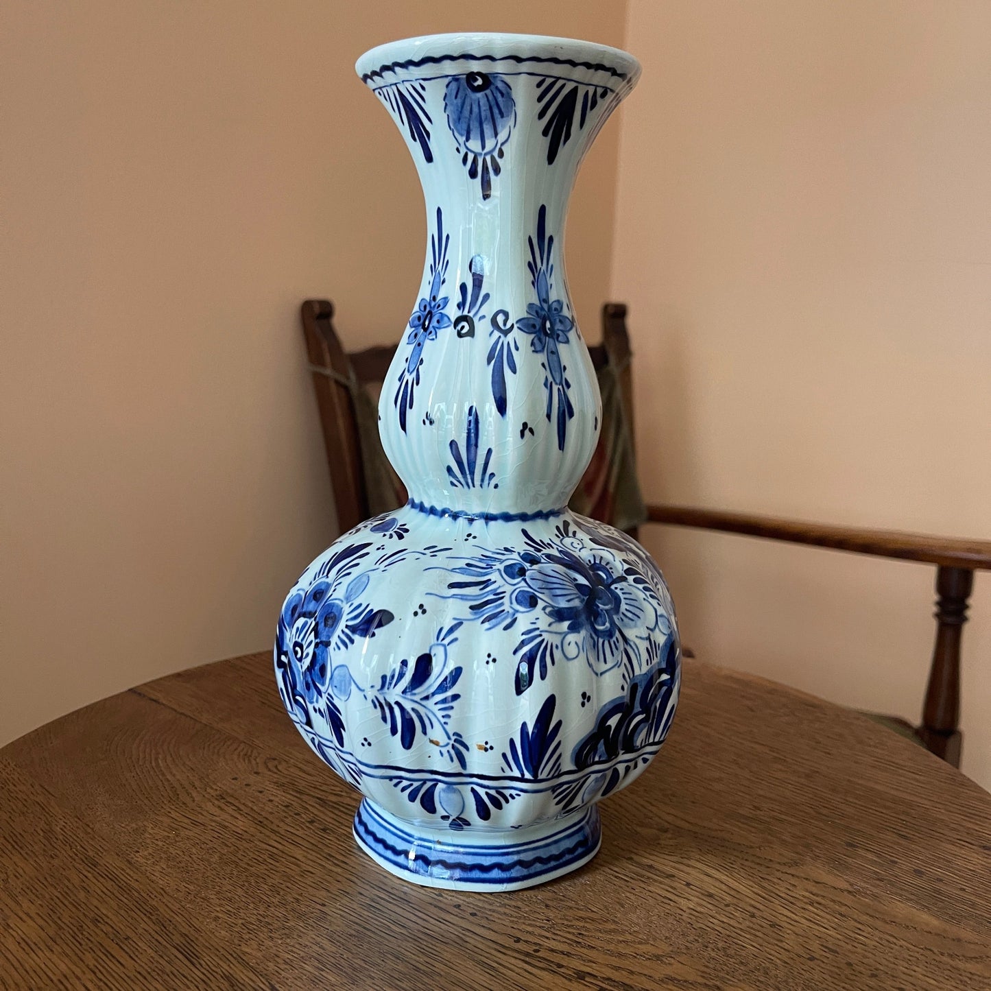 Blue and white ceramic vase on a wooden table with a beige wall background