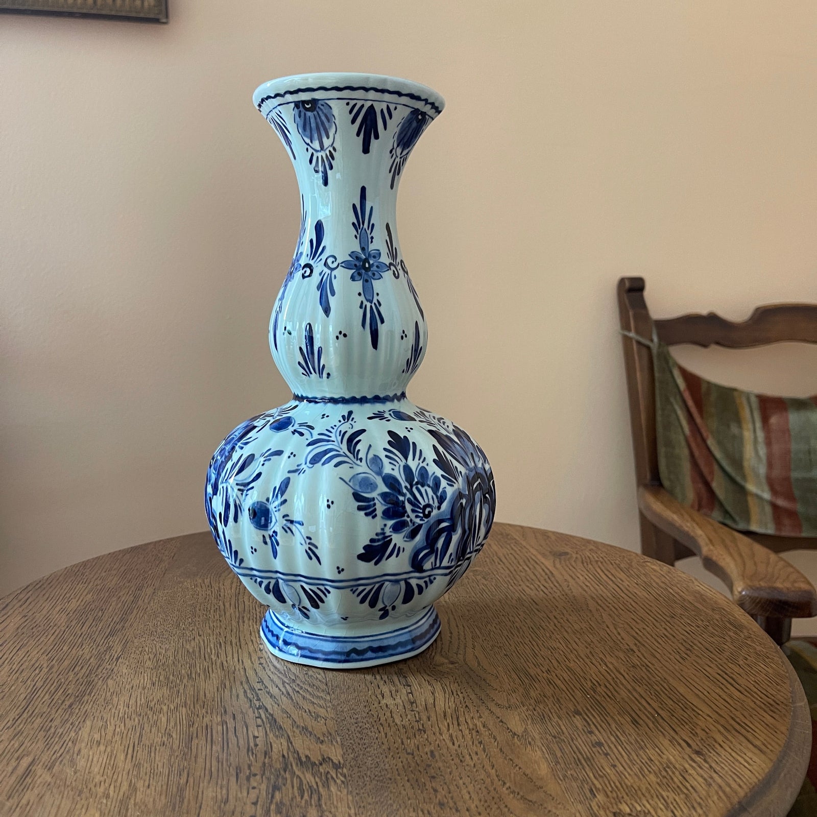Blue and white ceramic vase on a wooden table with a chair in the background