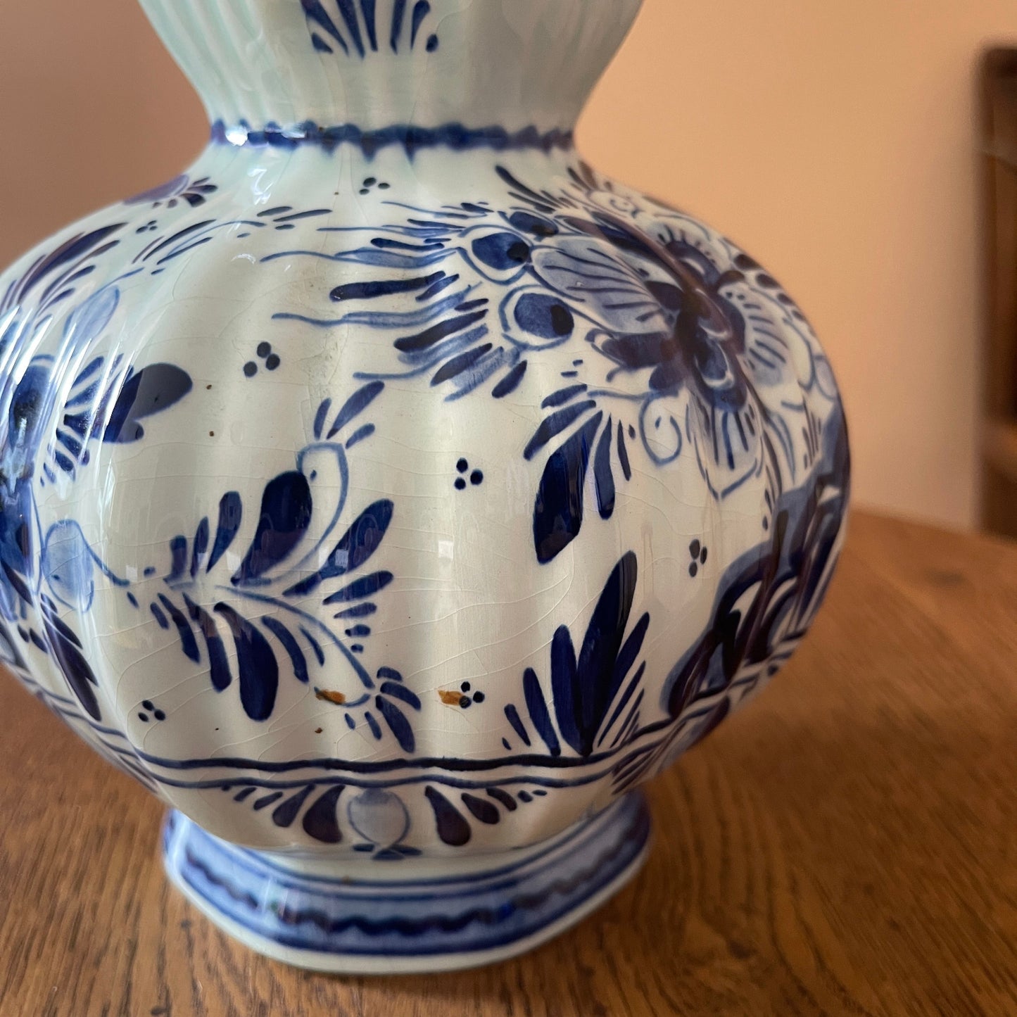 White ceramic vase with blue floral patterns on a wooden surface