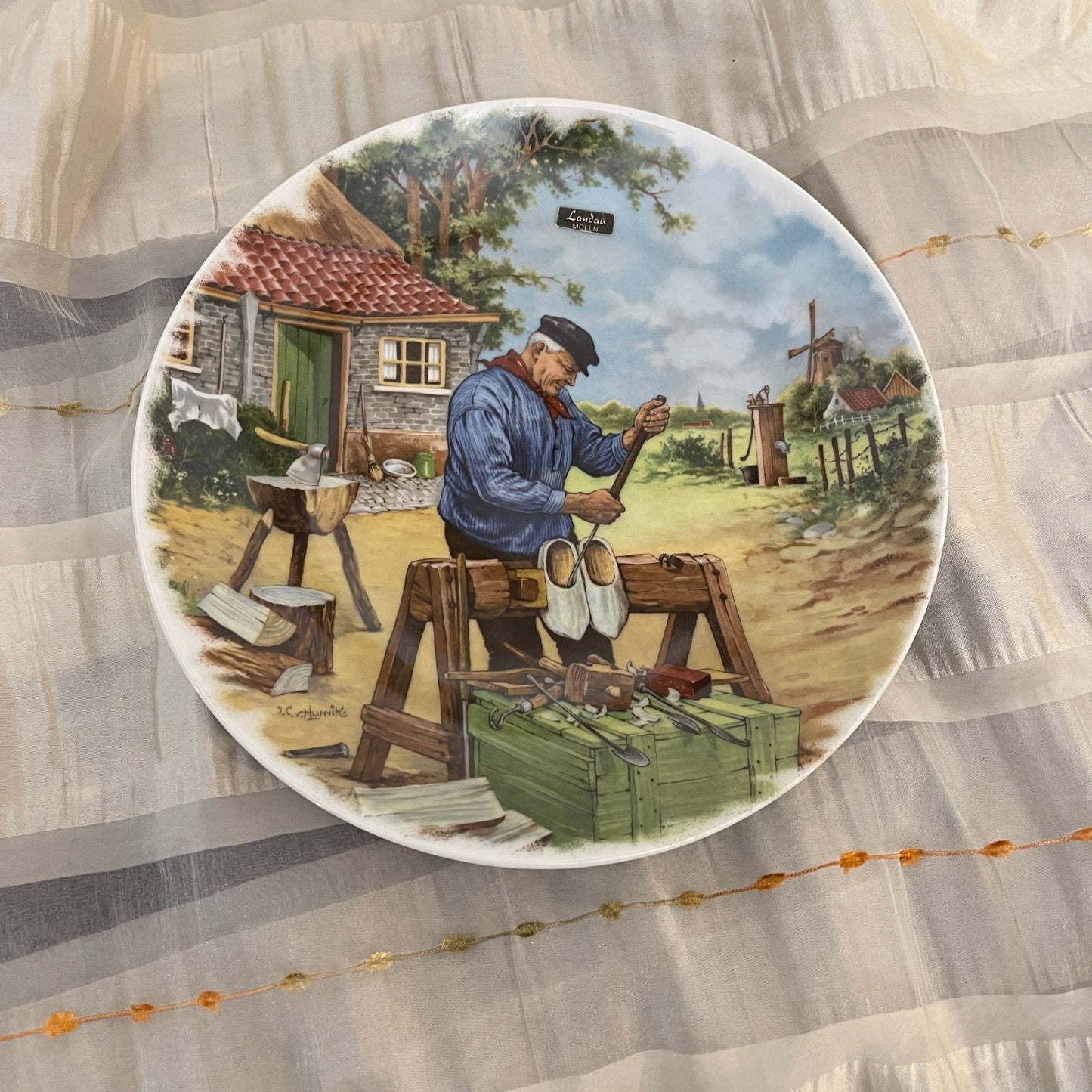 Decorative plate with a shoe polisher scene on a textured fabric background