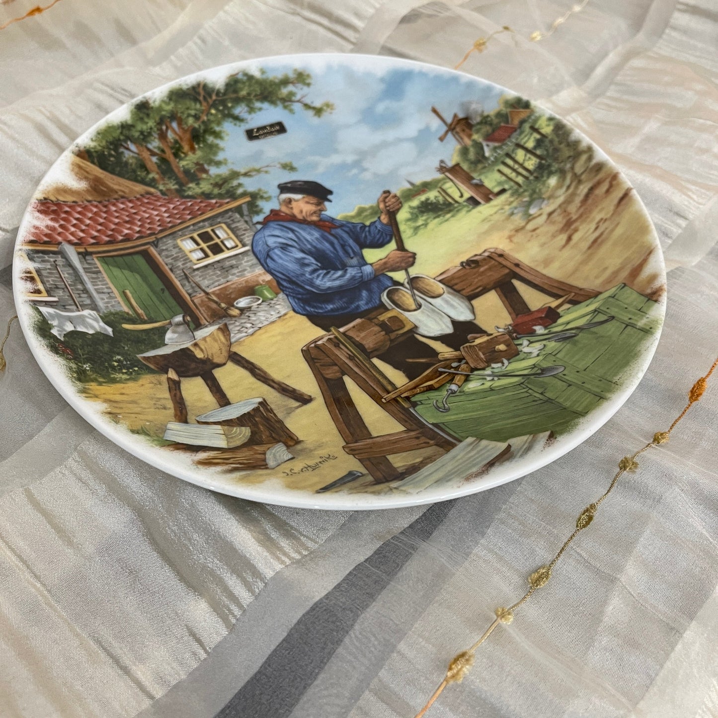 Decorative plate with a scene of a man working on a farm, placed on a textured surface.