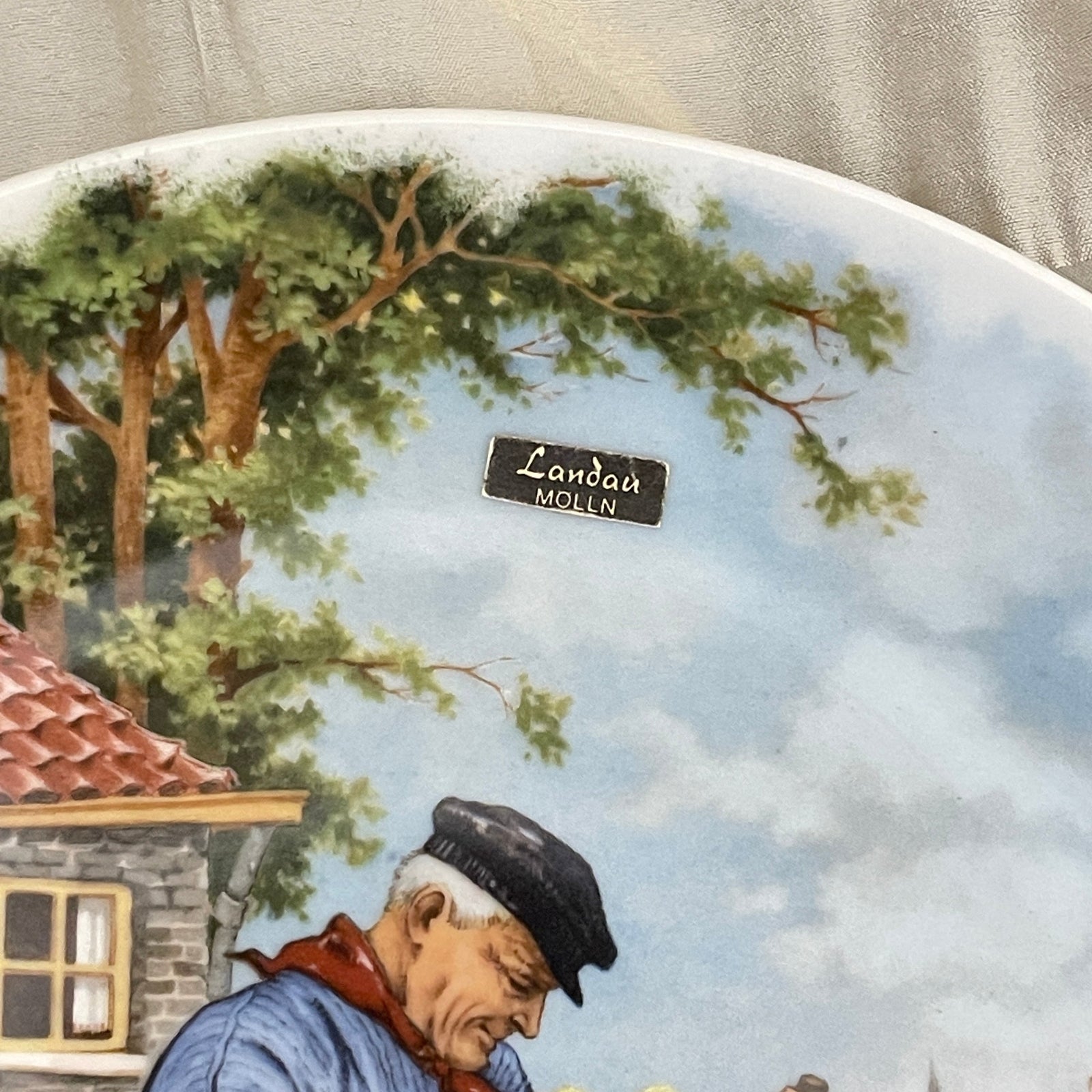 Decorative plate with a scenic landscape and a person, featuring the brand 'Landa Molln'.