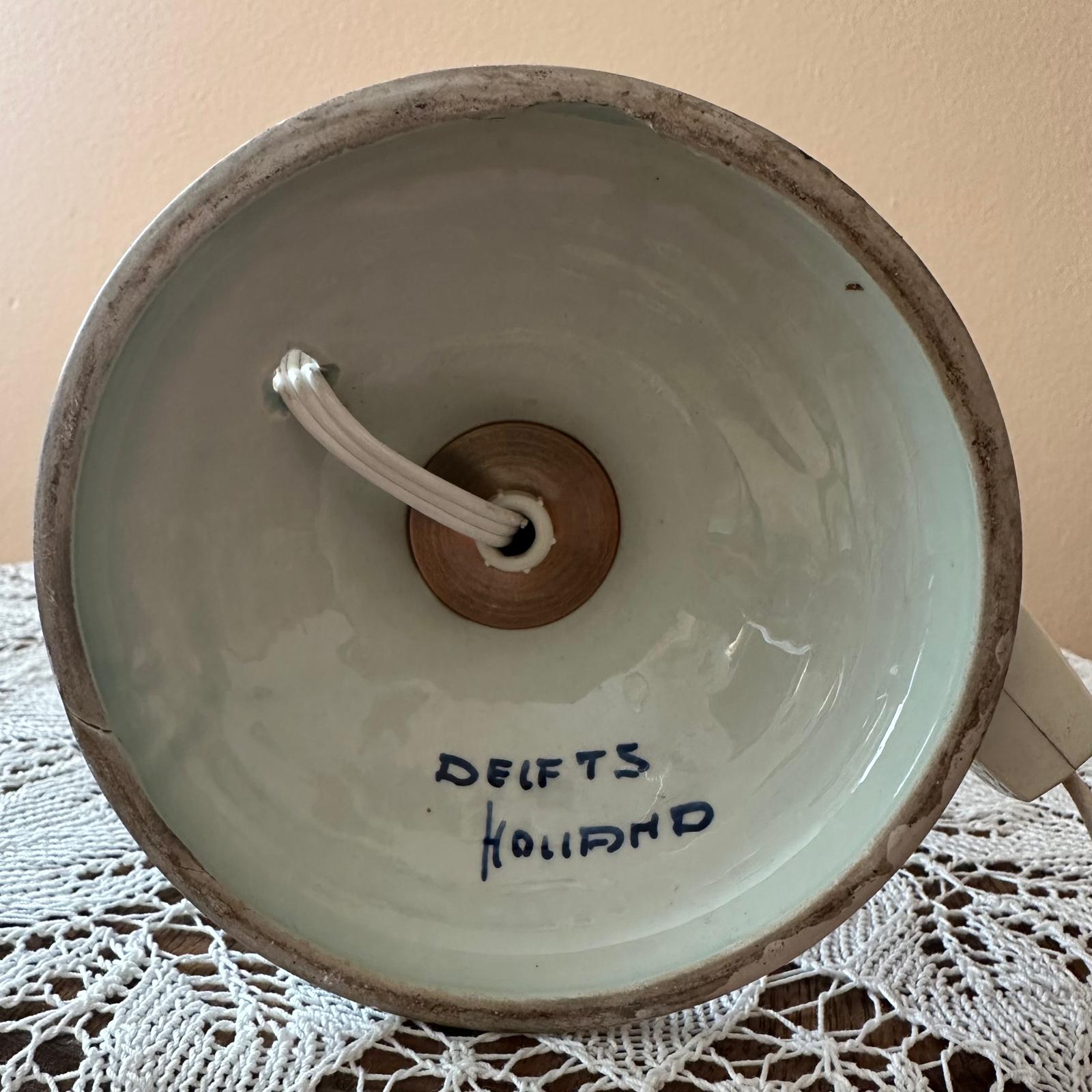 Ceramic bowl with wooden handle and 'Delfts Holland' inscription on a lace tablecloth.