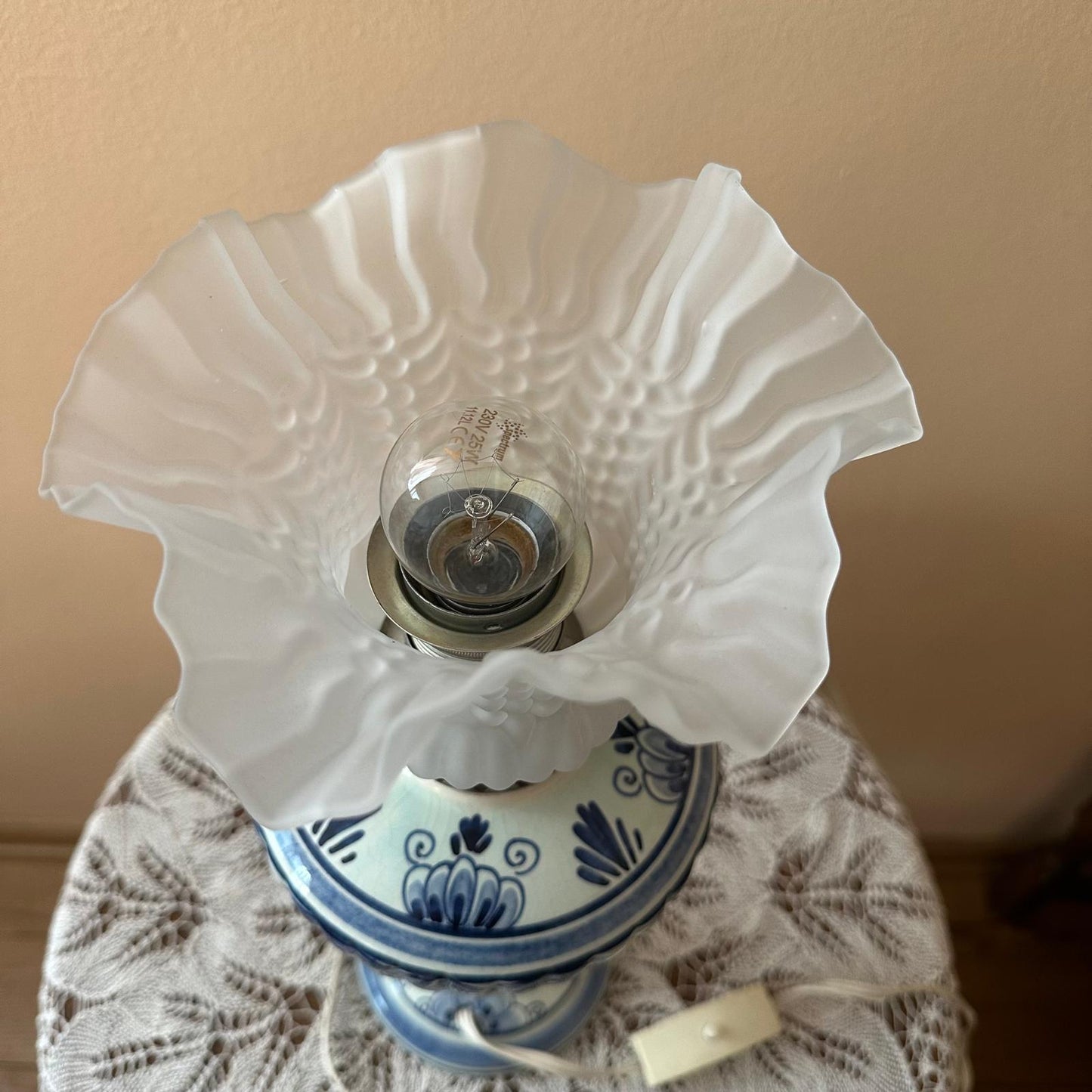 Vintage-style lamp with white glass shade and blue base on a textured surface.