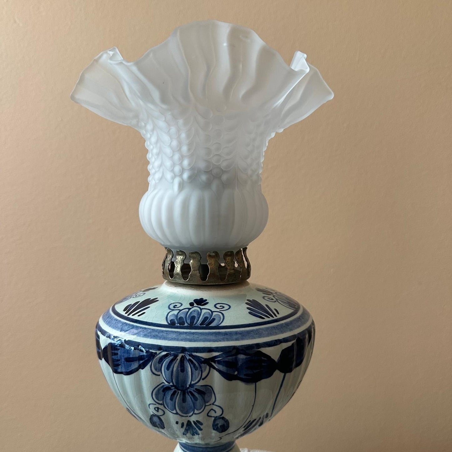 Decorative lamp with white glass shade and blue floral design on a beige background