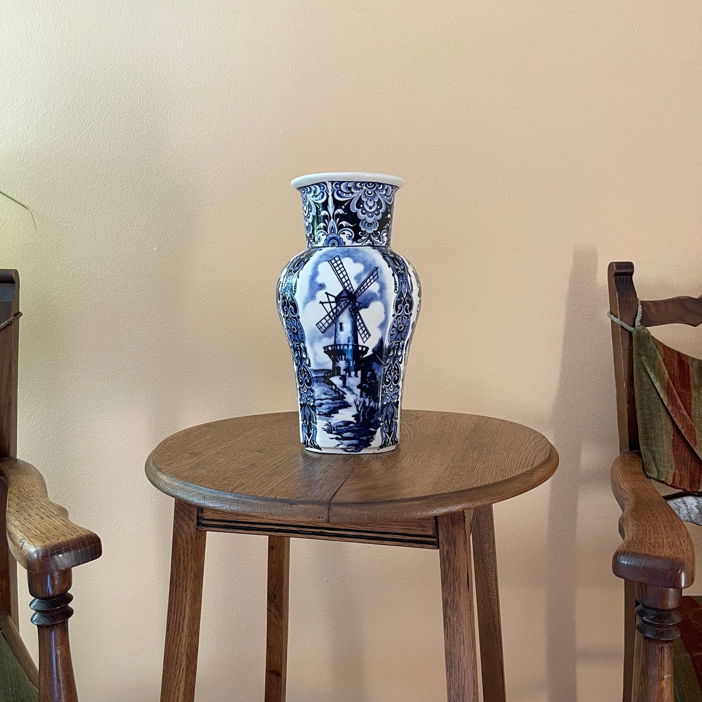 Blue and white ceramic vase on a wooden stool against a beige wall