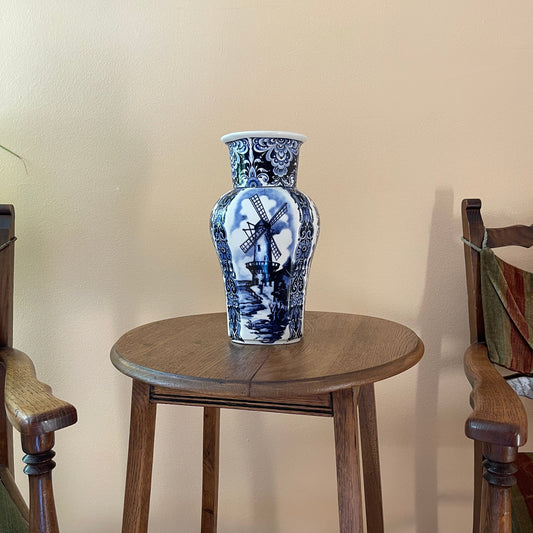 Blue and white ceramic vase on a wooden stool against a beige wall