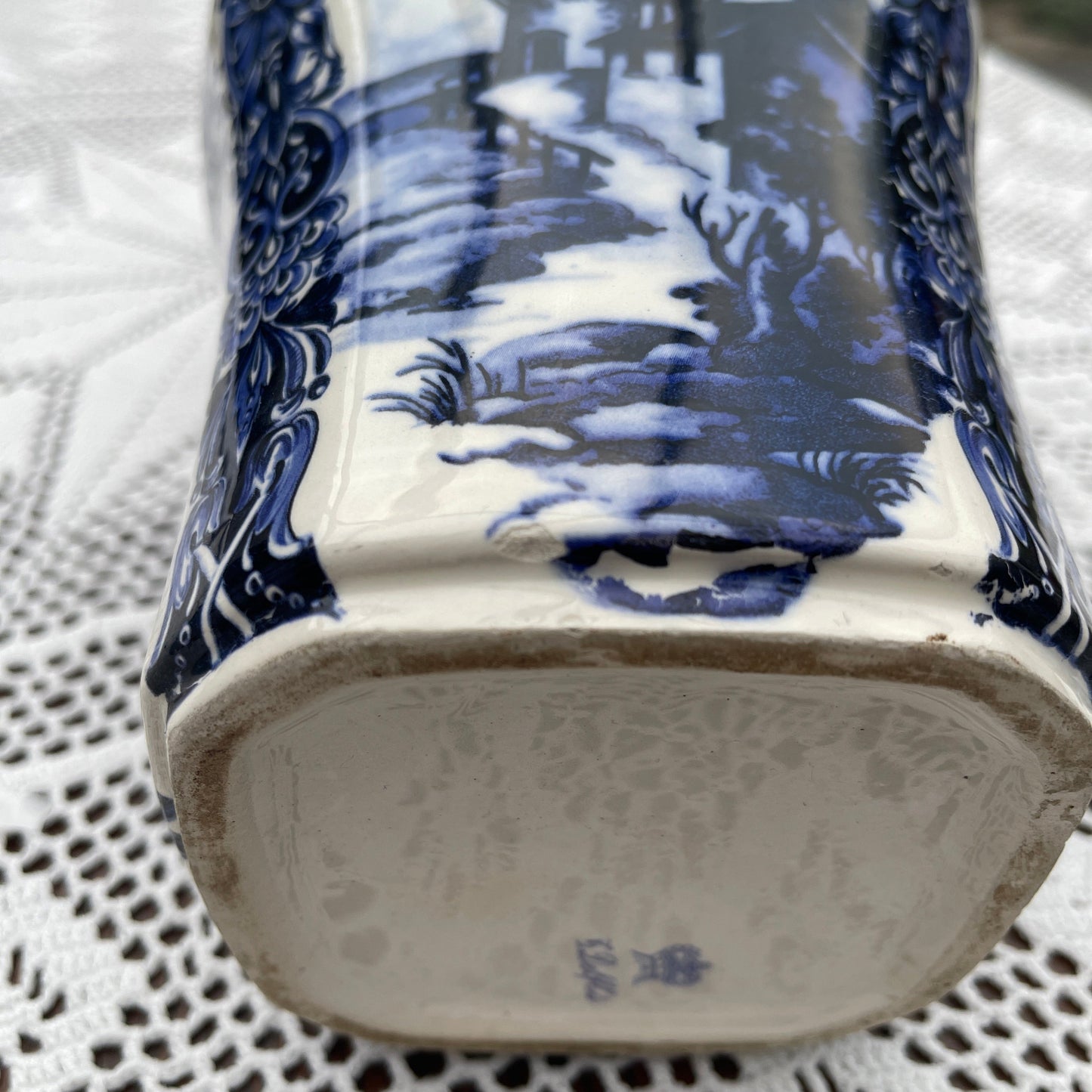 Close-up of a blue and white ceramic vase with intricate patterns on a textured surface.