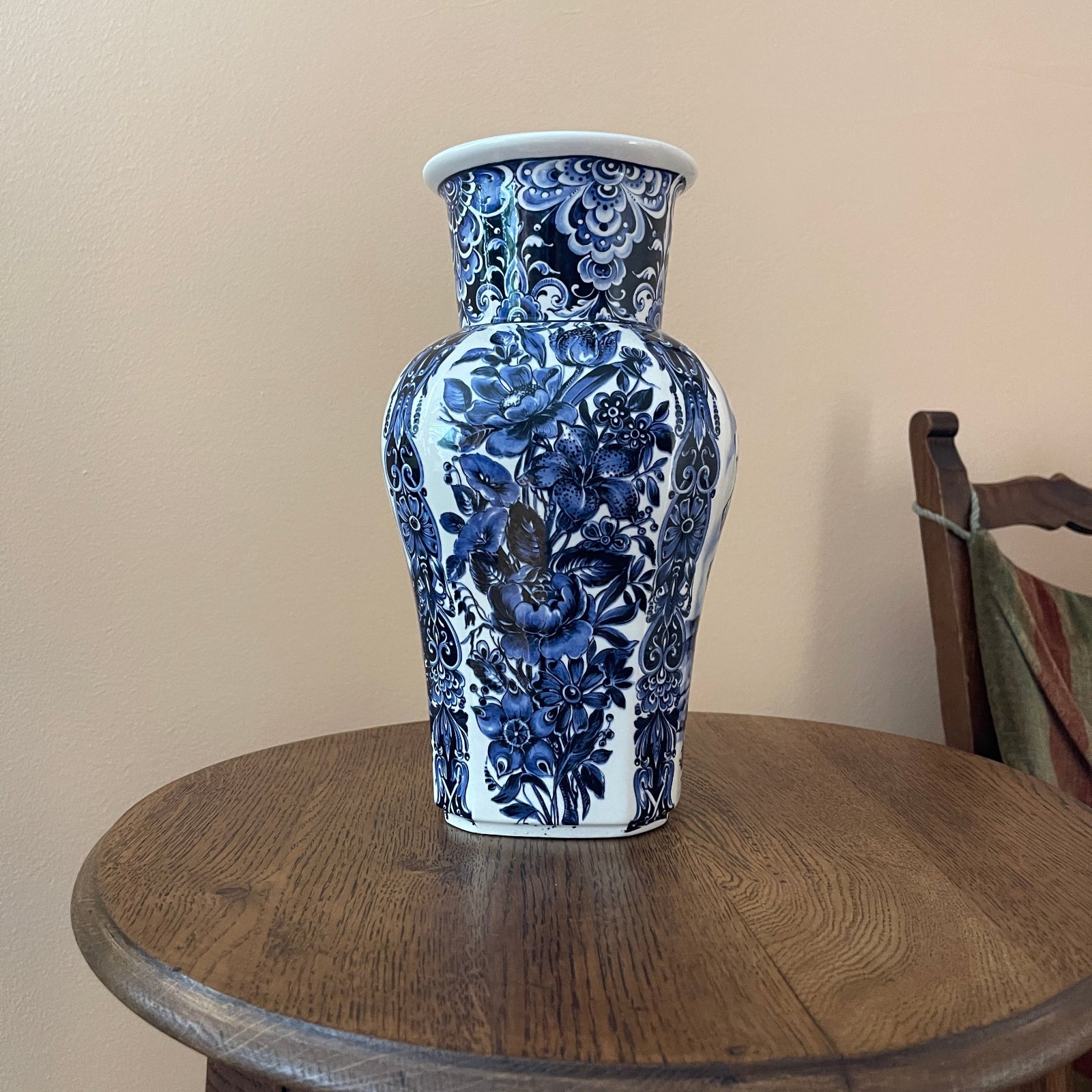 Blue floral-patterned vase on a wooden table against a beige wall