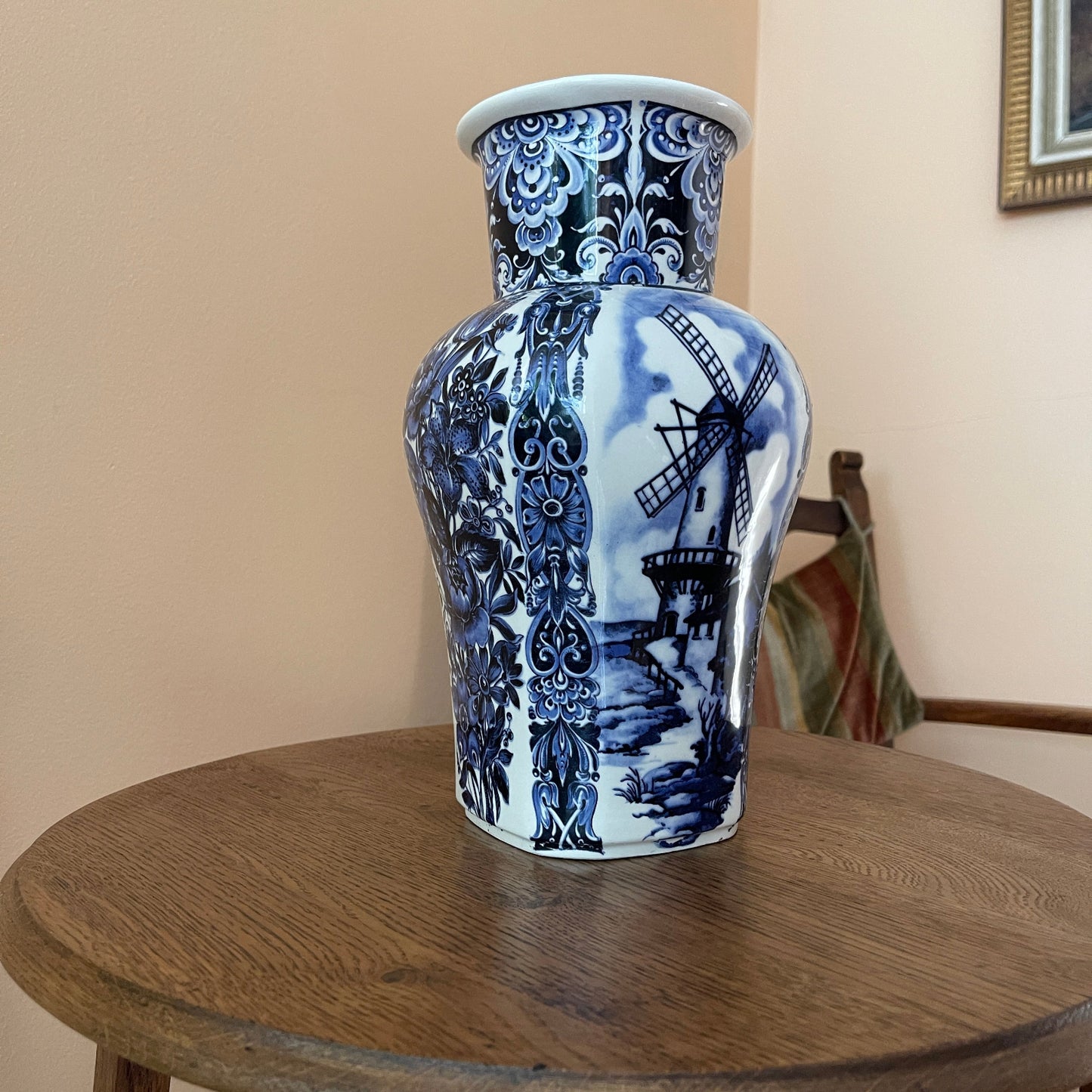 Blue and white ceramic vase with windmill design on a wooden table