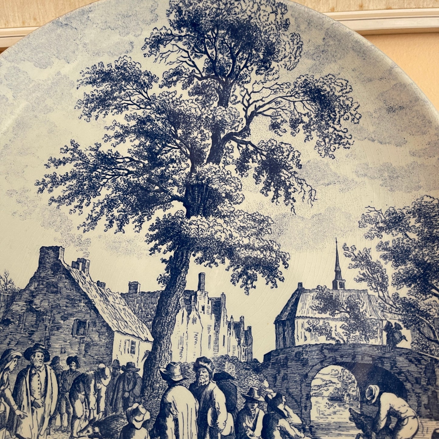 Vintage-style illustration of a village scene with people and a large tree.