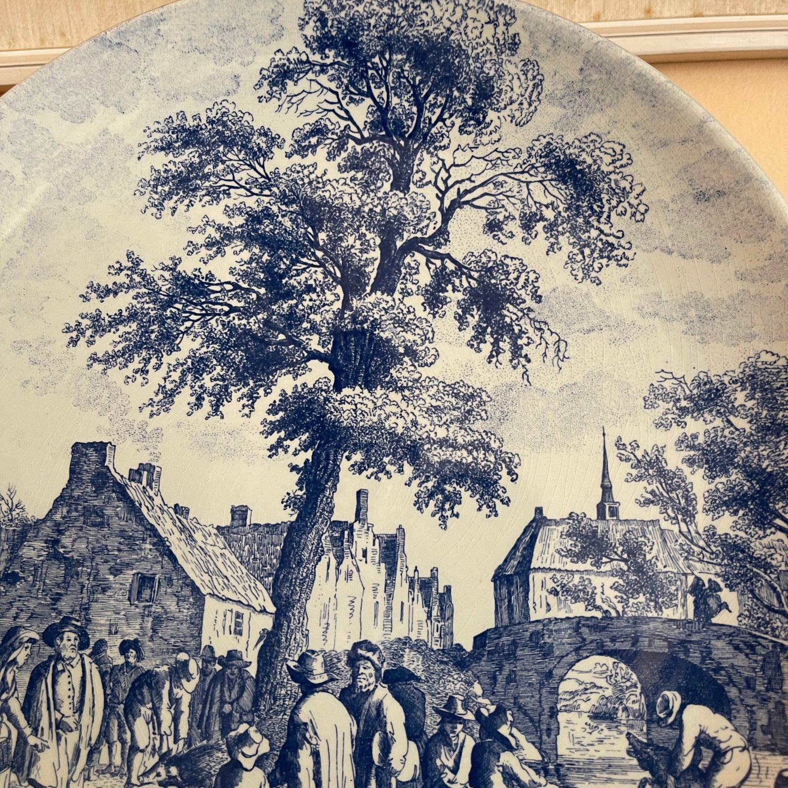 Vintage-style illustration of a village scene with people and a large tree.