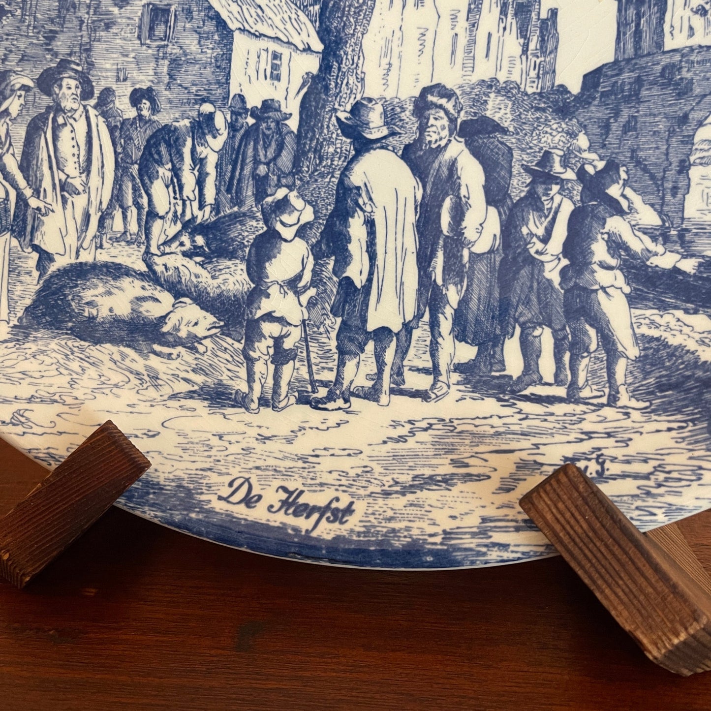 Vintage-style illustration of a group of people in a village scene with 'De Herfst' text.
