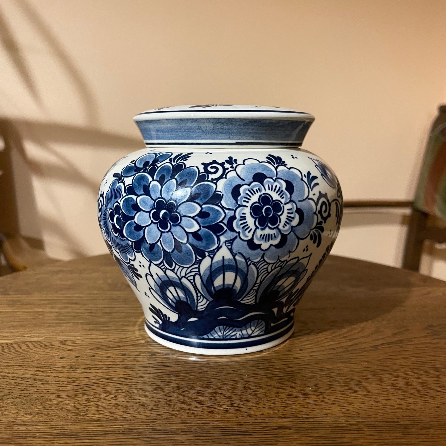 Blue and white floral-patterned ceramic jar on a wooden surface with a neutral background
