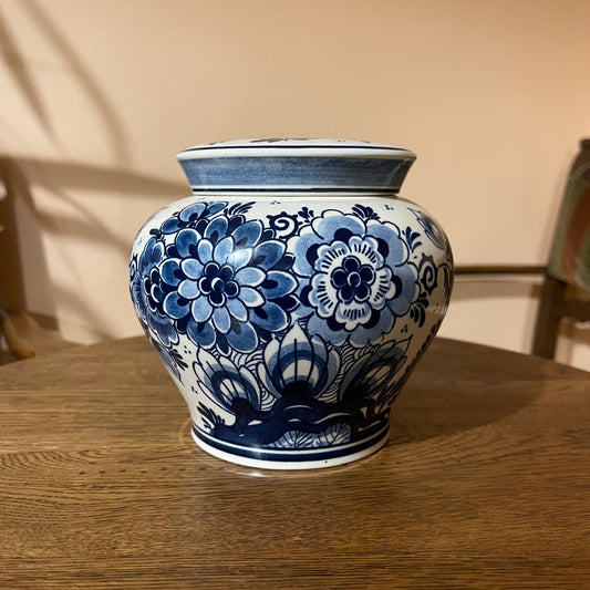 Blue and white floral-patterned ceramic jar on a wooden surface with a neutral background